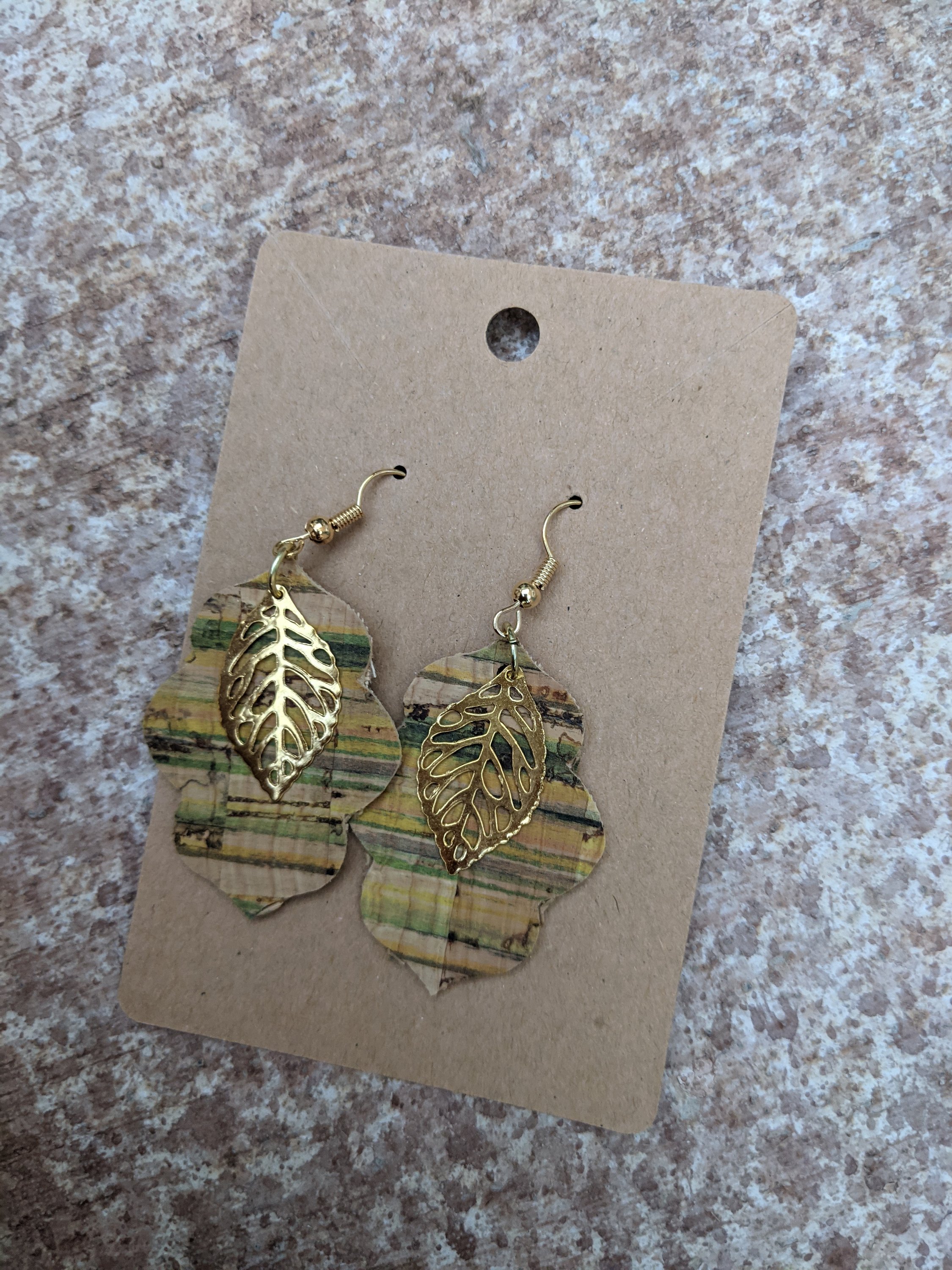 Handmade light green cork earrings featuring a delicate leaf filigree charm, showcasing their unique design and lightweight nature.