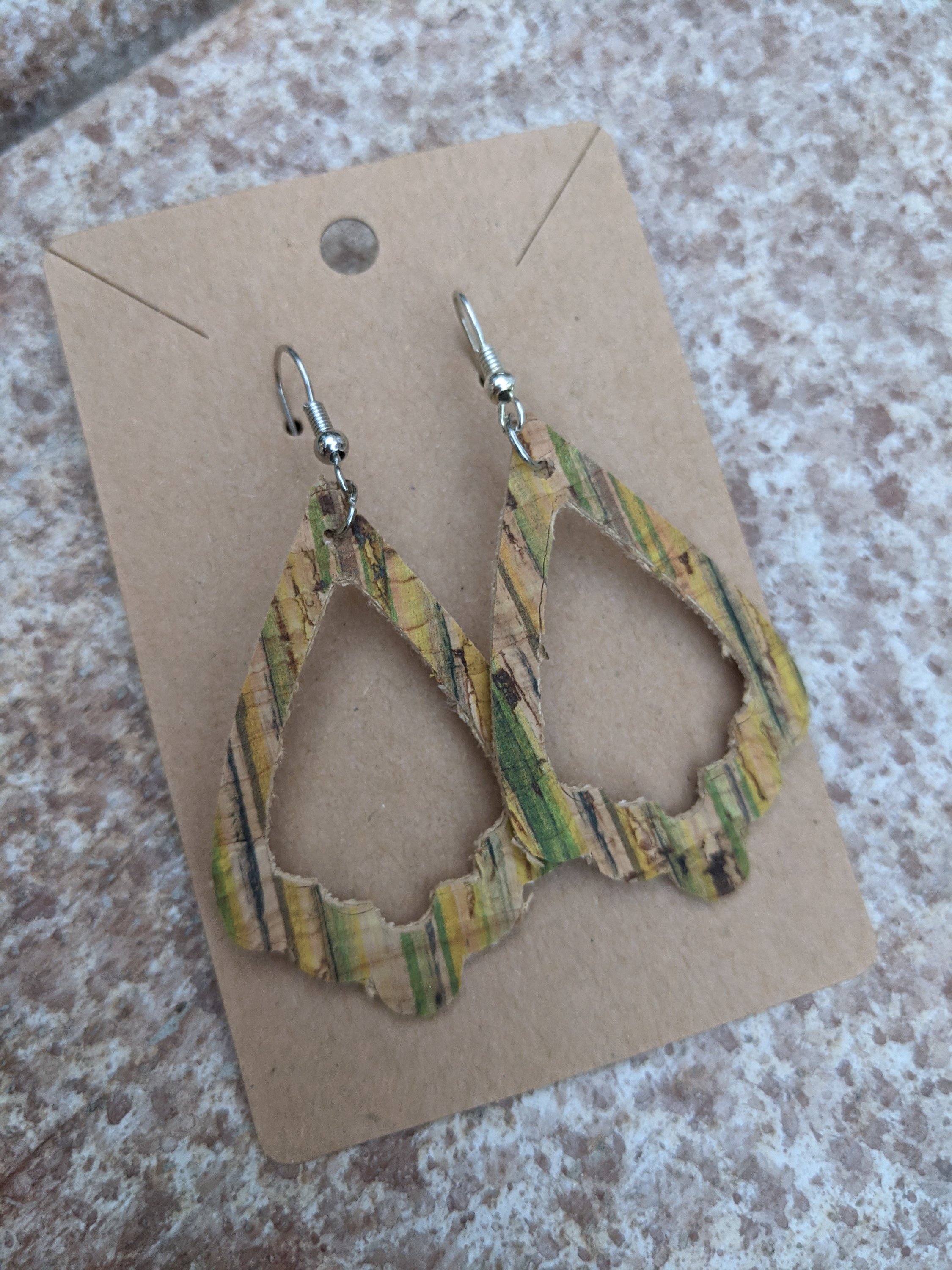 Handmade light green cork earrings featuring a delicate leaf filigree charm, showcasing their unique design and lightweight nature.