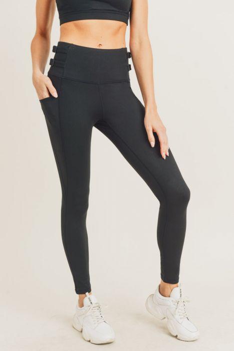 A pair of black highwaist leggings featuring adjustable harness straps on the sides, designed for comfort and style during workouts.