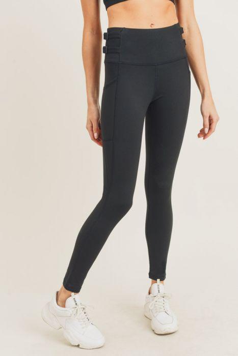 A pair of black highwaist leggings featuring adjustable harness straps on the sides, designed for comfort and style during workouts.