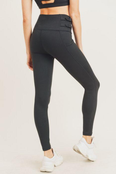 A pair of black highwaist leggings featuring adjustable harness straps on the sides, designed for comfort and style during workouts.