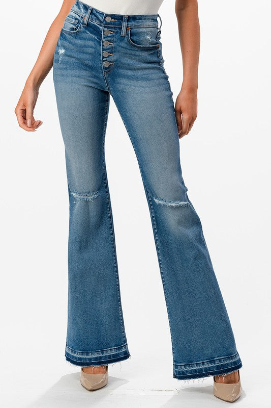 High rise bootcut jeans featuring distress and fray hem, styled on a model.