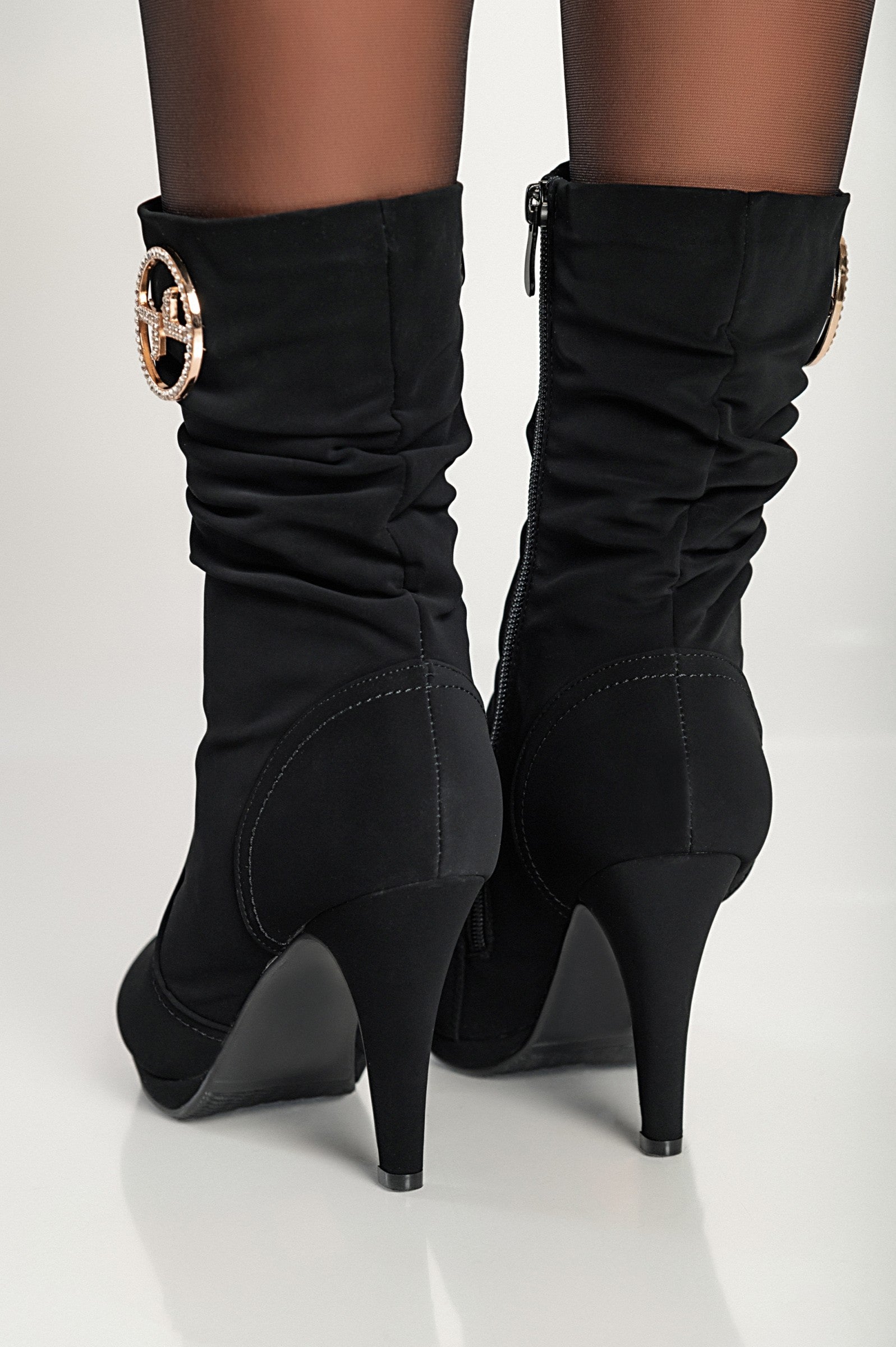 Elegant black high-heeled ankle boots with pointed toe and inside zipper closure, featuring decorative details.