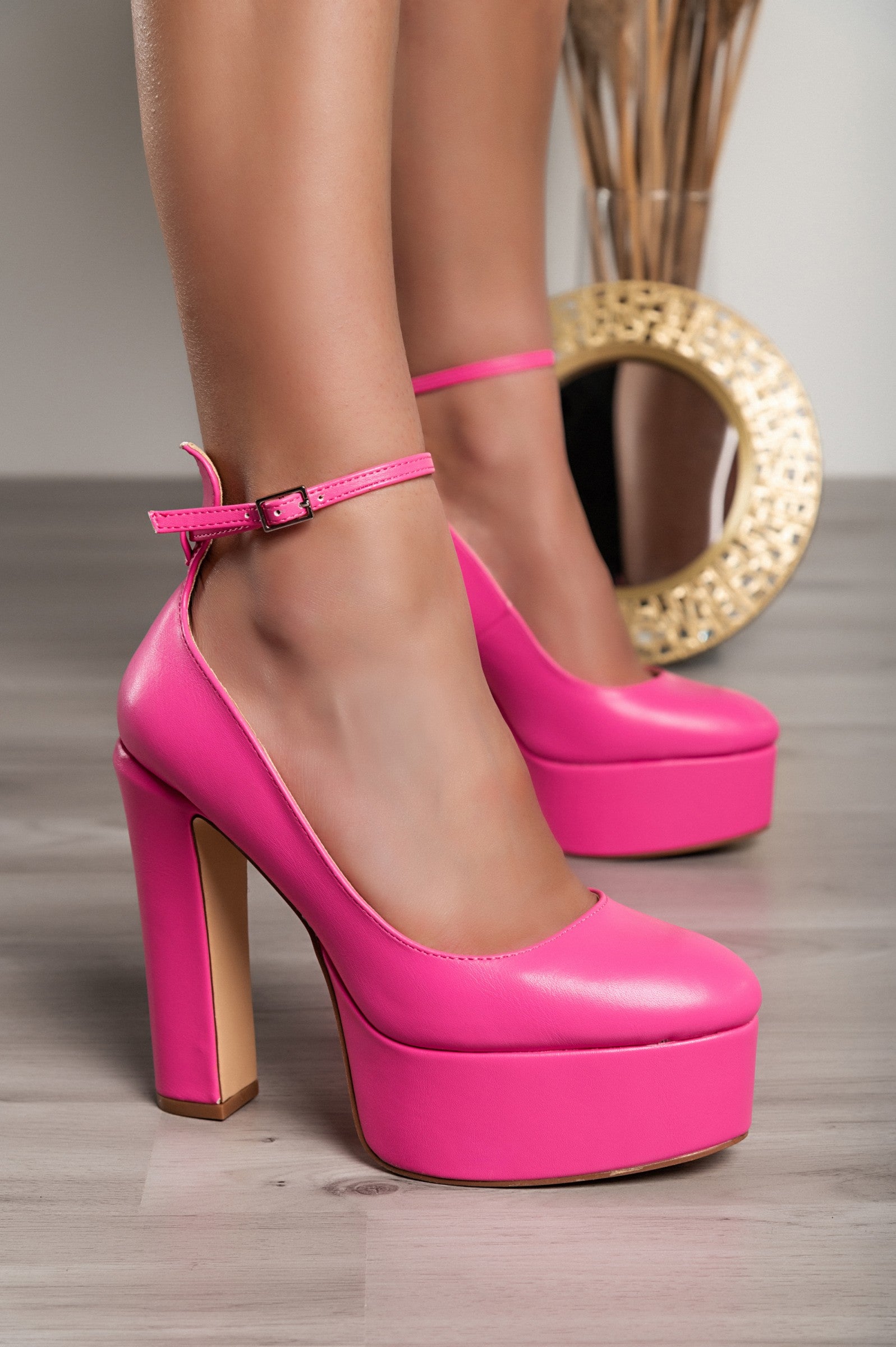 Fuchsia high-heeled shoes made of faux leather with a pointed toe and ankle strap.