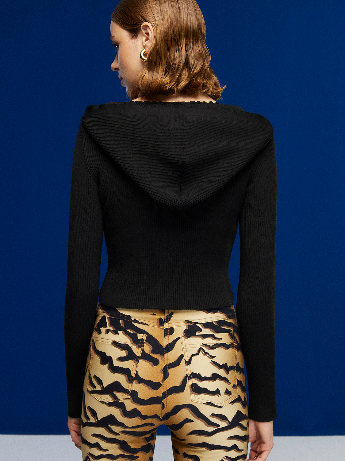 A stylish Hooded Knit Crop Top featuring a V-neck and long sleeves, designed in a trendy leopard print pattern.