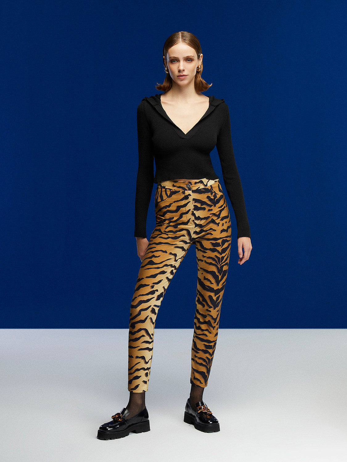 A stylish Hooded Knit Crop Top featuring a V-neck and long sleeves, designed in a trendy leopard print pattern.