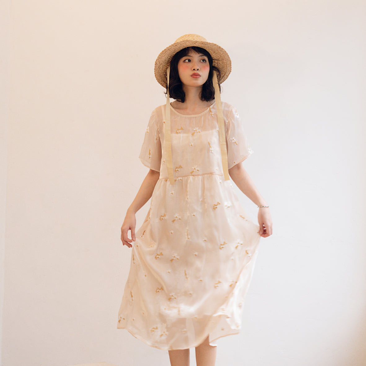 The Hotaru Dress showcasing elegant organza chiffon fabric with floral embroidery and a stylish bow tie at the back.