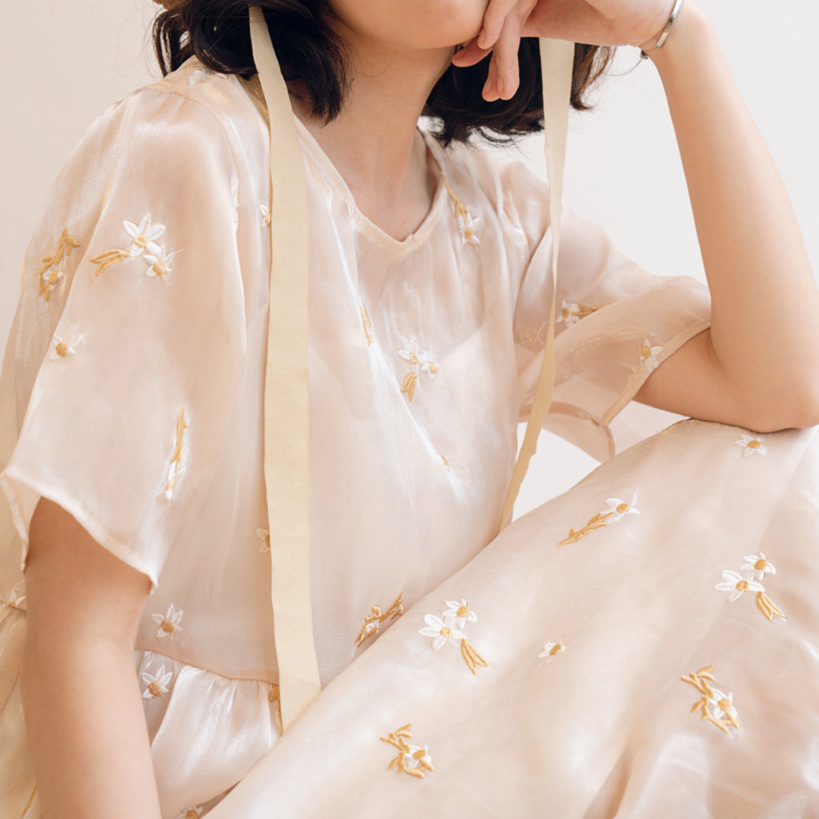 The Hotaru Dress showcasing elegant organza chiffon fabric with floral embroidery and a stylish bow tie at the back.