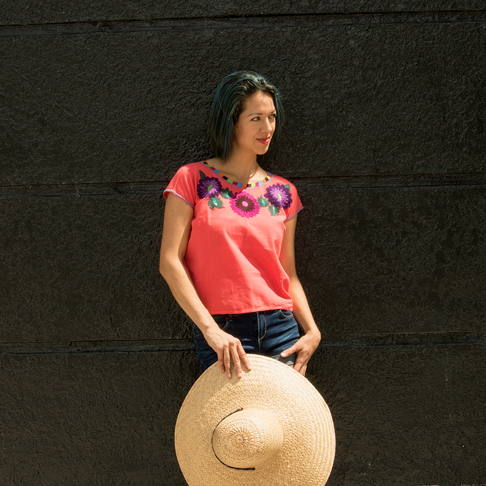 A vibrant Huipil blouse featuring colorful embroidered flowers, handcrafted by artisans from Oaxaca, Mexico, showcasing intricate designs and cultural significance.