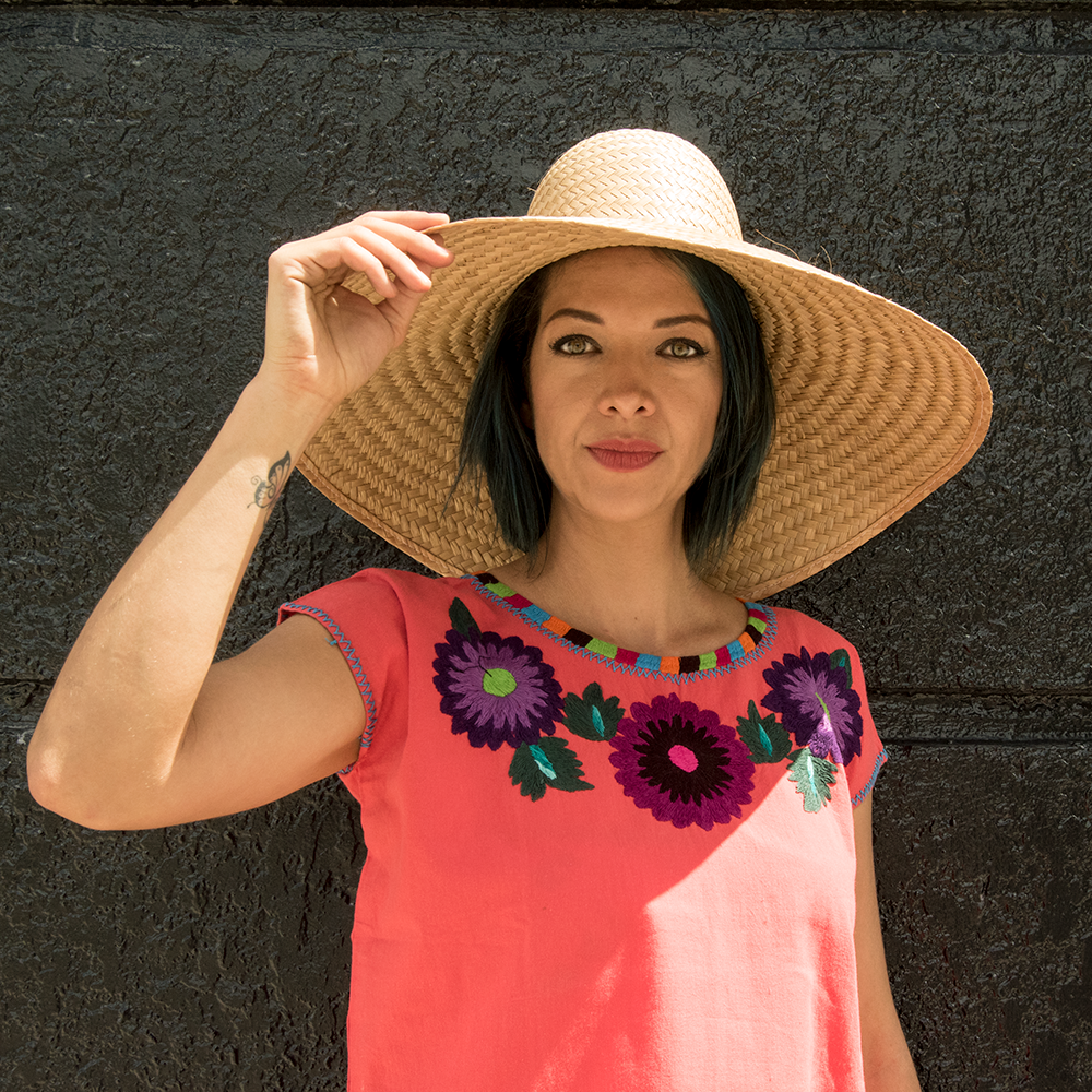 A vibrant Huipil blouse featuring colorful embroidered flowers, handcrafted by artisans from Oaxaca, Mexico, showcasing intricate designs and cultural significance.