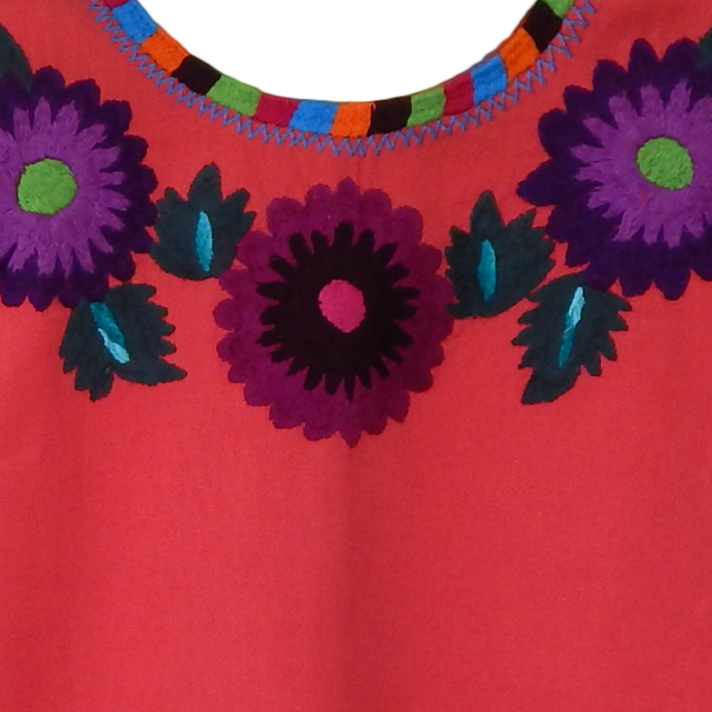 A vibrant Huipil blouse featuring colorful embroidered flowers, handcrafted by artisans from Oaxaca, Mexico, showcasing intricate designs and cultural significance.