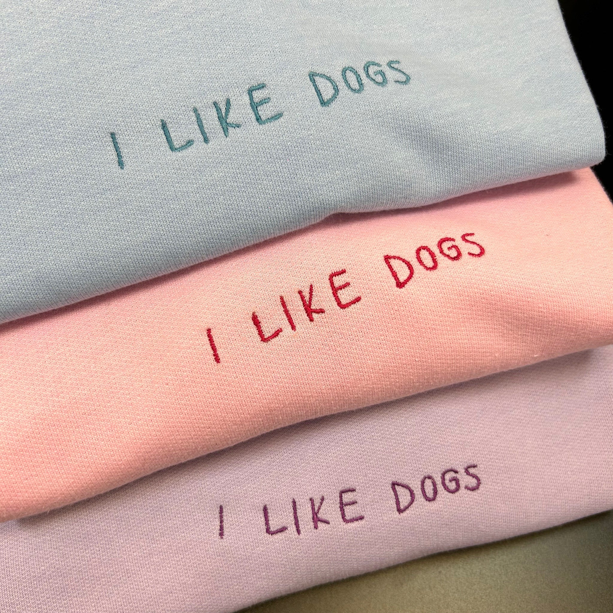 A cozy 'I Like Dogs' sweatshirt in pastel pink, blue, and lilac, showcasing a simple yet impactful message for dog lovers.