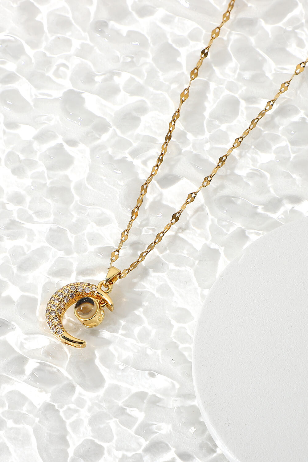 Inlaid Cubic Zirconia Moon Pendant Necklace featuring a delicate moon design and sparkling cubic zirconia, displayed in a flat lay studio setting.