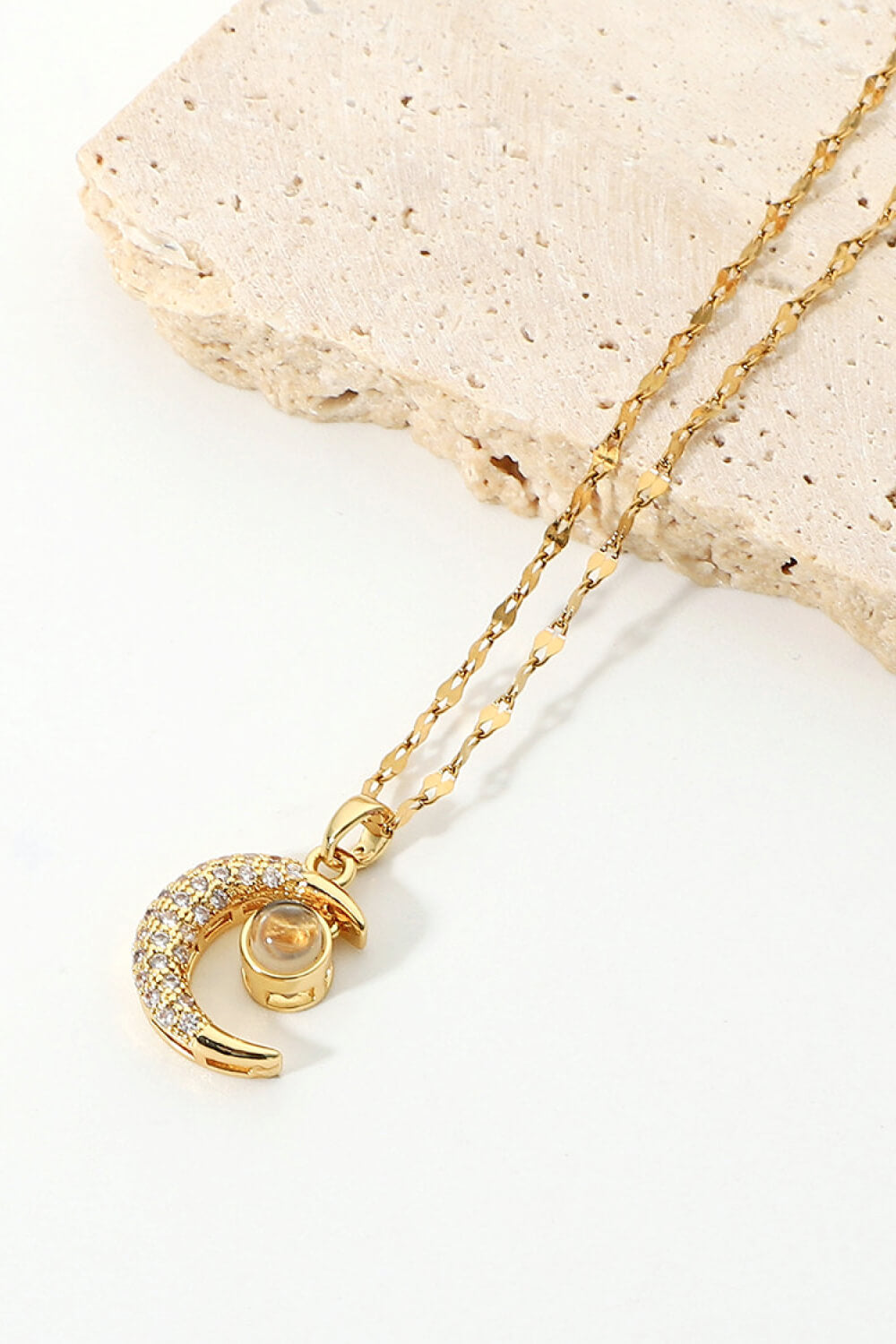 Inlaid Cubic Zirconia Moon Pendant Necklace featuring a delicate moon design and sparkling cubic zirconia, displayed in a flat lay studio setting.