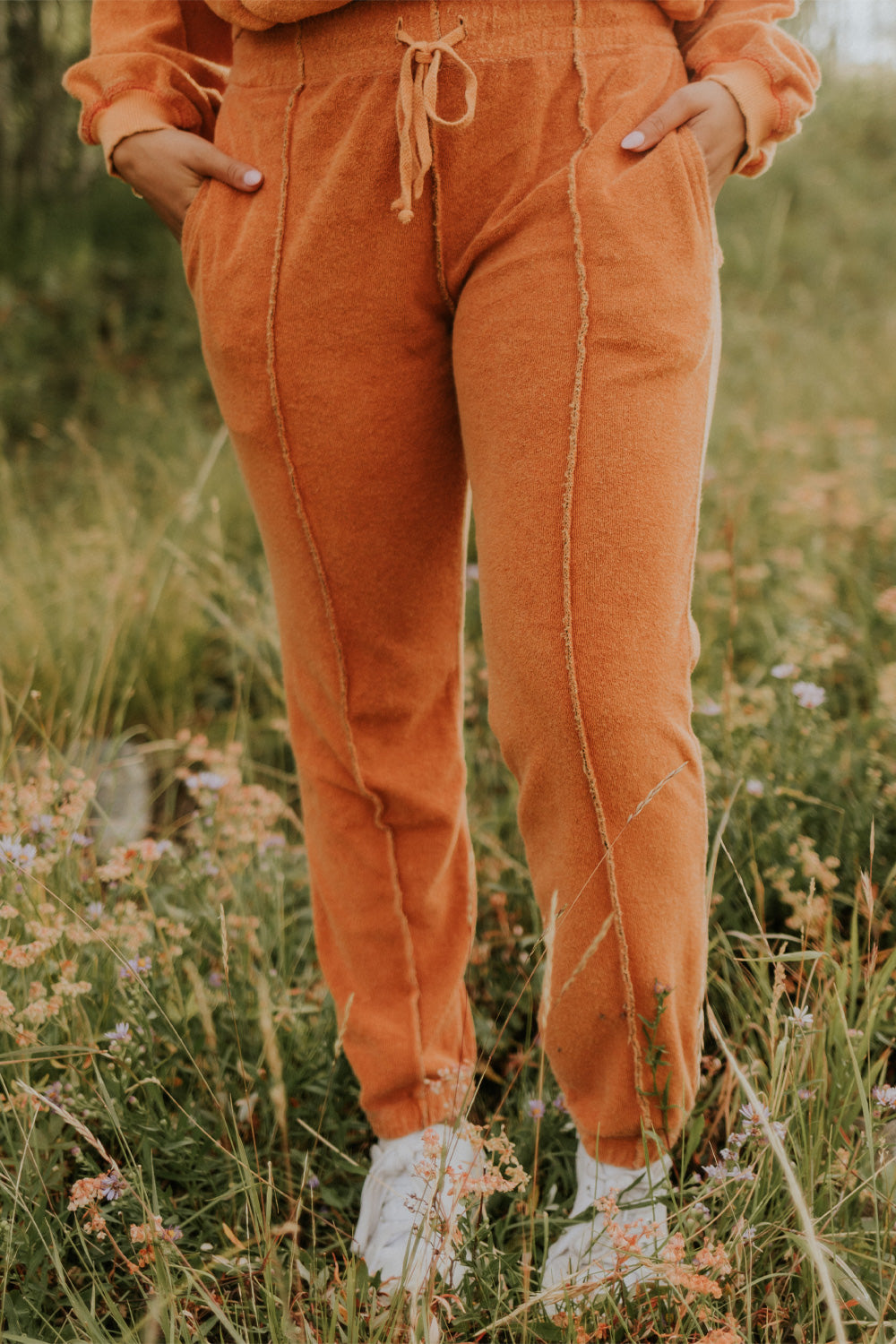 A pair of stylish It’s All Good Joggers in orange, featuring a drawstring waist, pockets, and elastic hem, showcasing a modern front seam design.