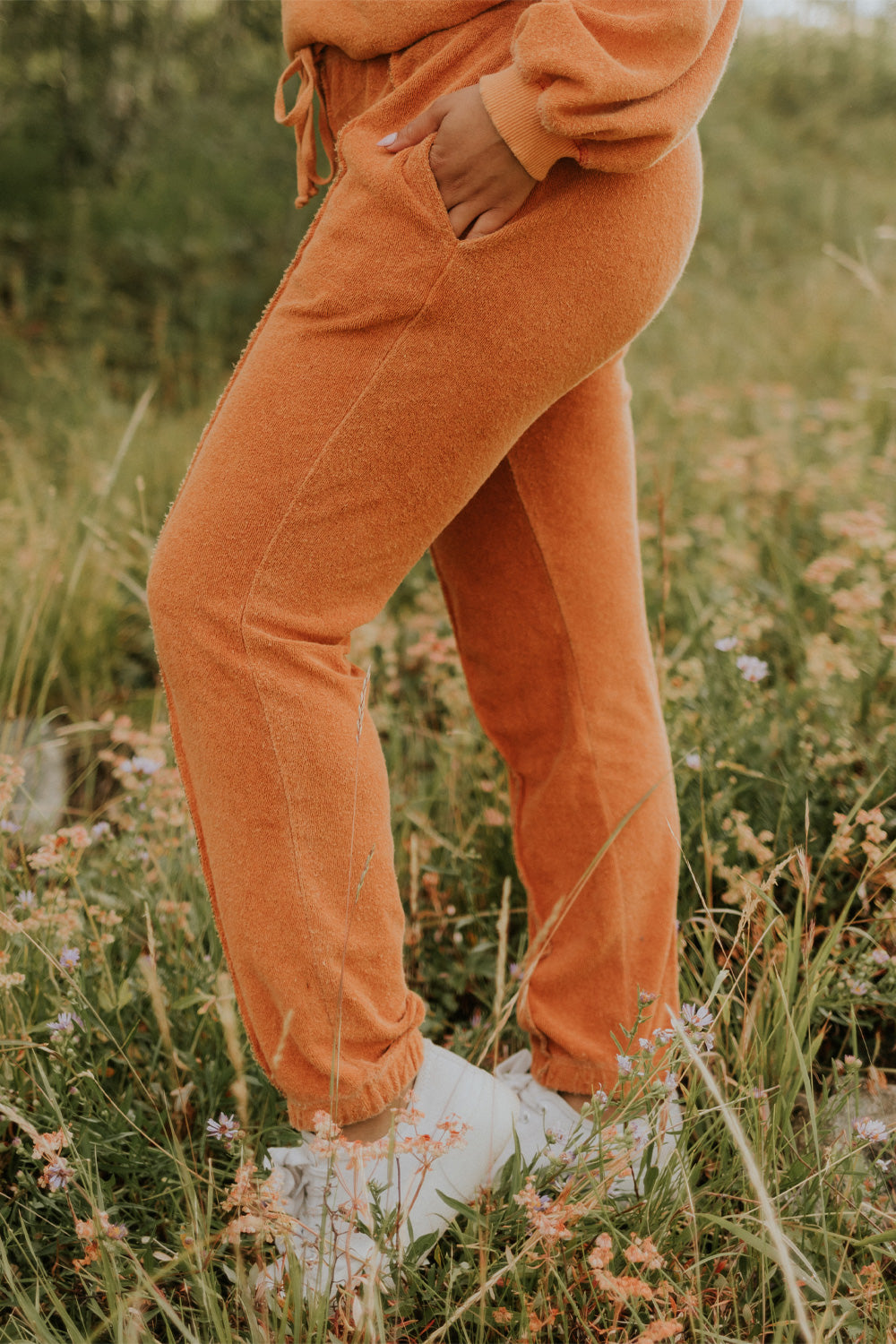 A pair of stylish It’s All Good Joggers in orange, featuring a drawstring waist, pockets, and elastic hem, showcasing a modern front seam design.