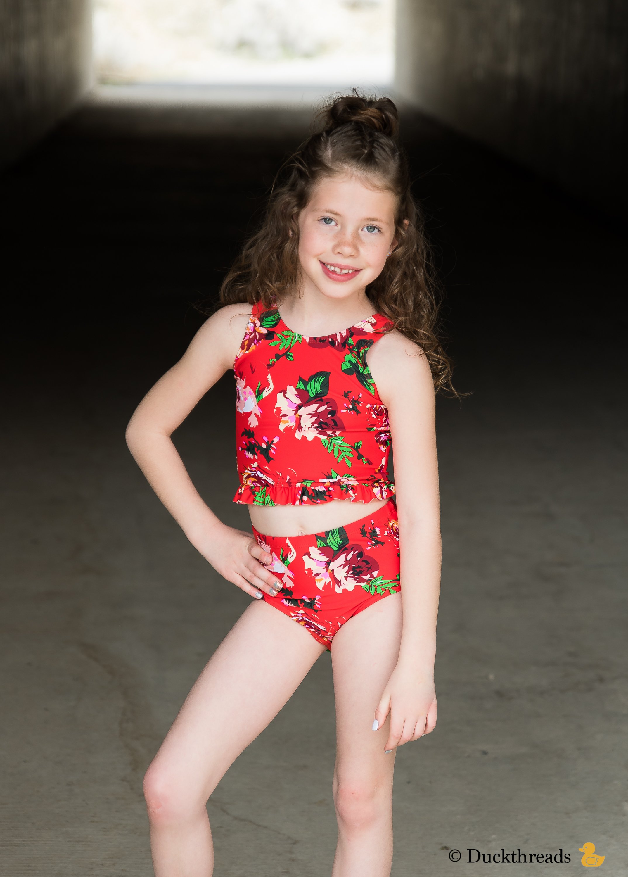 Janela Bay Red Floral Little Ruffle Swim Top featuring a vibrant floral print and playful ruffle detail along the bottom.