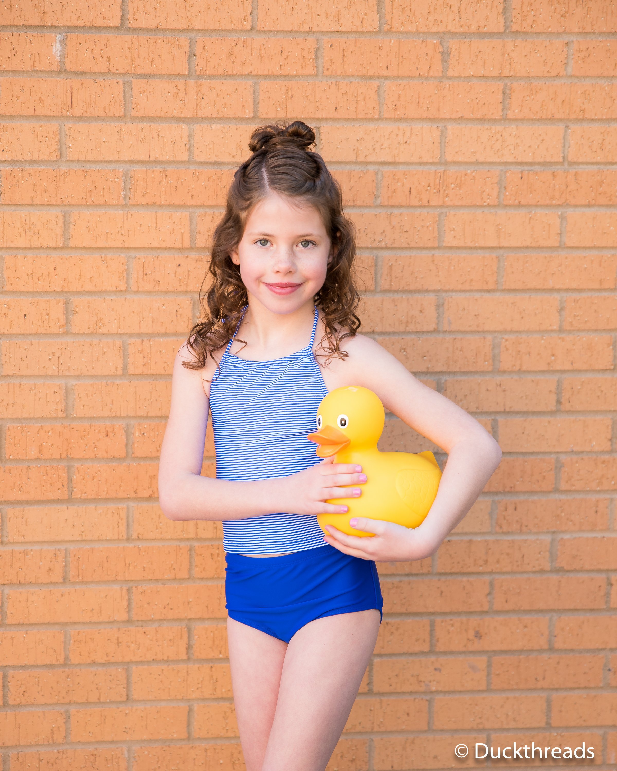 Janela Bay Royal Blue Stripe Swim Top featuring a halter neck design and mini blue striped fabric, perfect for summer beach outings.