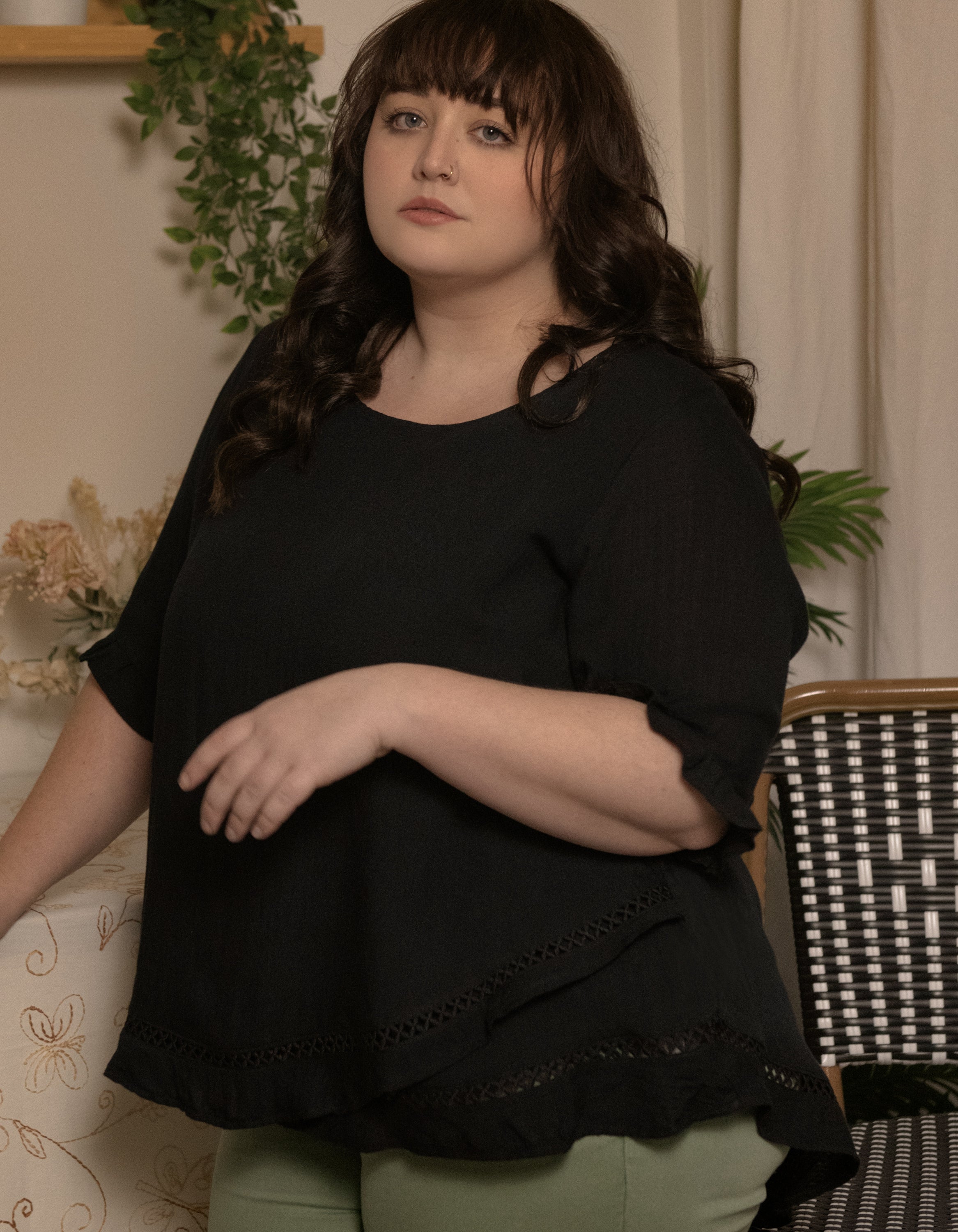 Jessy Top in Black featuring a relaxed fit, crossover hemline, and frilled cuffs, perfect for versatile styling.