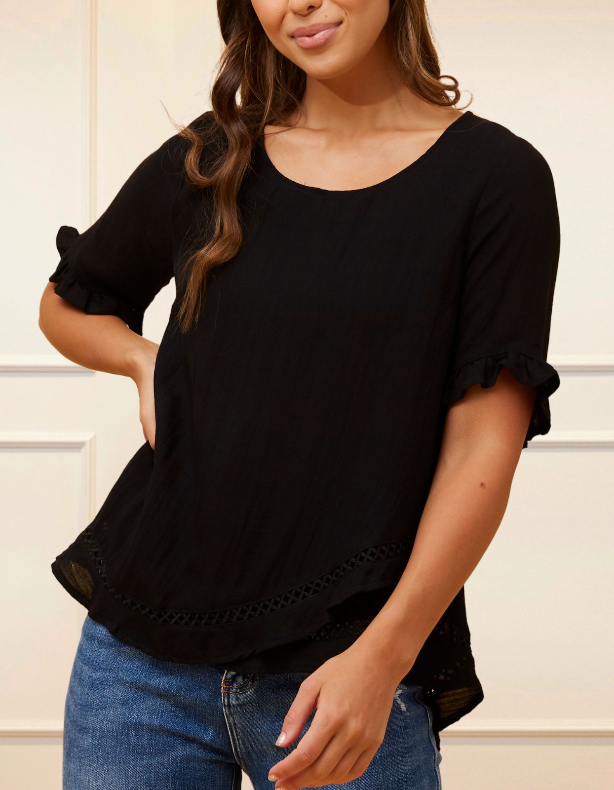 Jessy Top in Black featuring a relaxed fit, crossover hemline, and frilled cuffs, perfect for versatile styling.