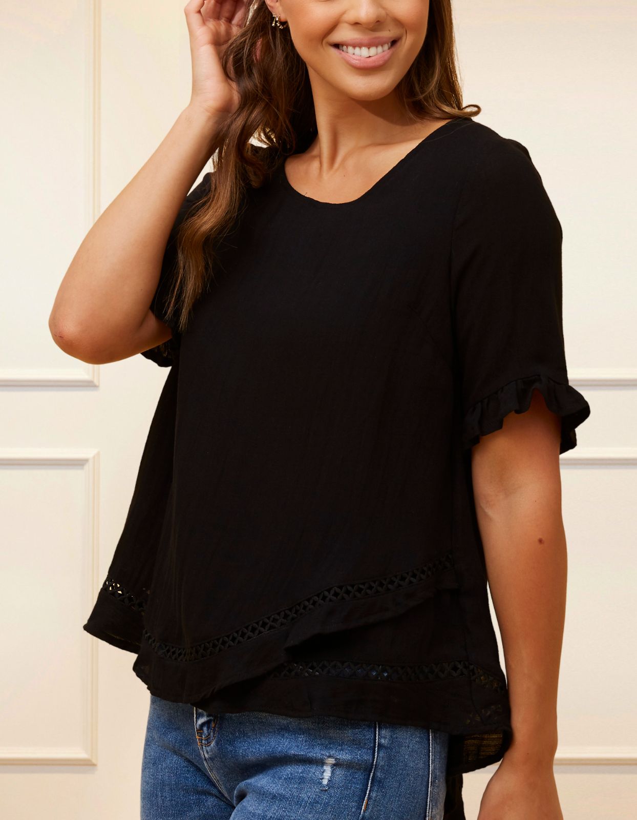 Jessy Top in Black featuring a relaxed fit, crossover hemline, and frilled cuffs, perfect for versatile styling.