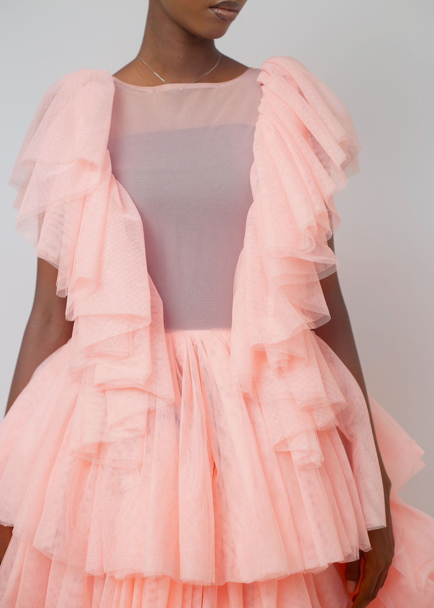 Kailani Dress in soft peach color featuring high-low hemline and layered ruffles, perfect for special occasions.