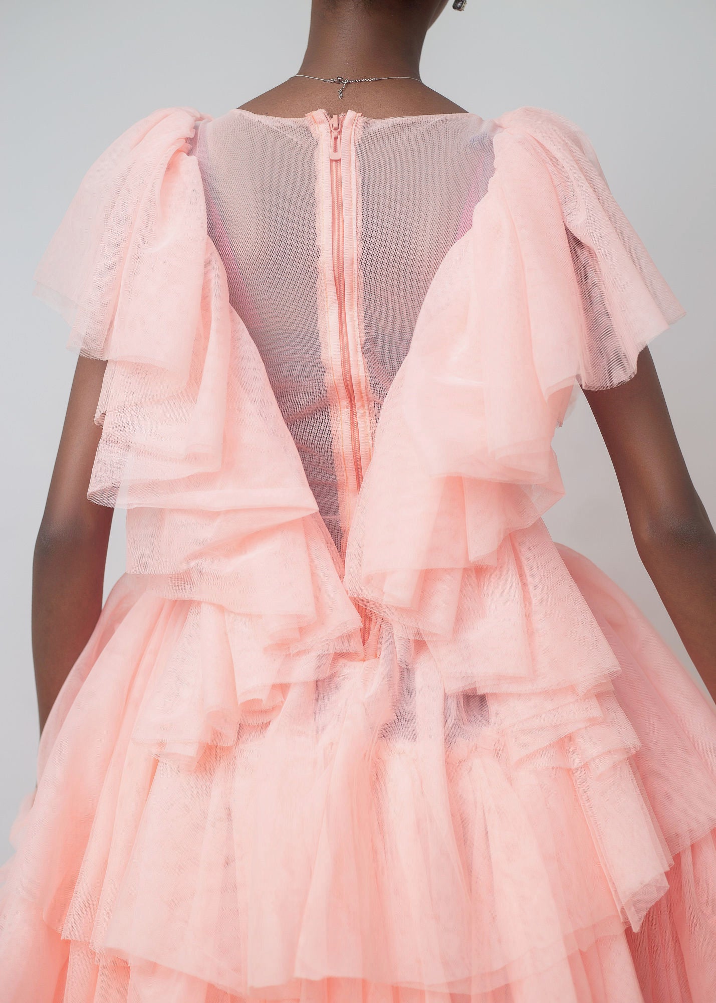 Kailani Dress in soft peach color featuring high-low hemline and layered ruffles, perfect for special occasions.