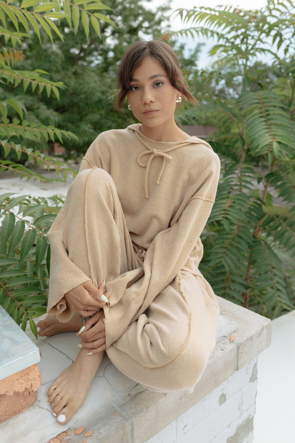 Kenny Hoodie in tan color featuring bell sleeves and a drawstring hood, made from organic cotton and recycled polyester.