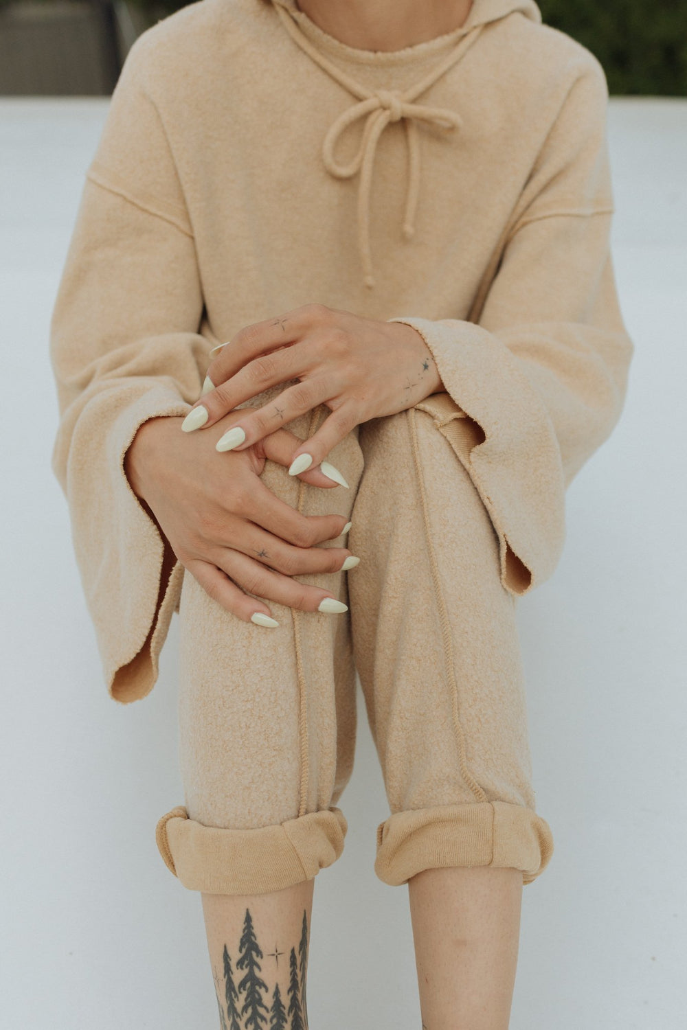 Kenny Hoodie in tan color featuring bell sleeves and a drawstring hood, made from organic cotton and recycled polyester.