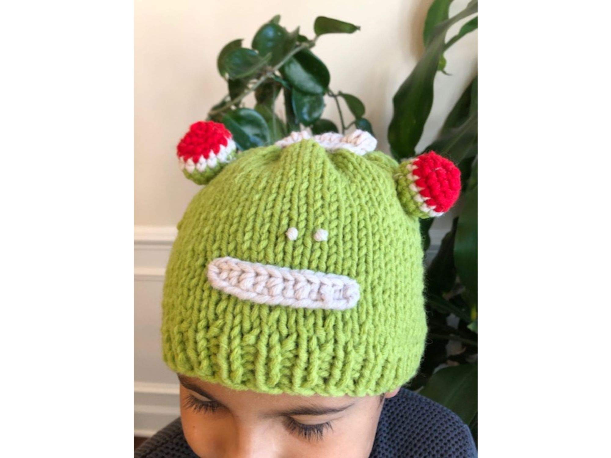 Hand-knitted frog wool beanie cap for kids, featuring a playful design and cozy fit, perfect for ages 2-7.