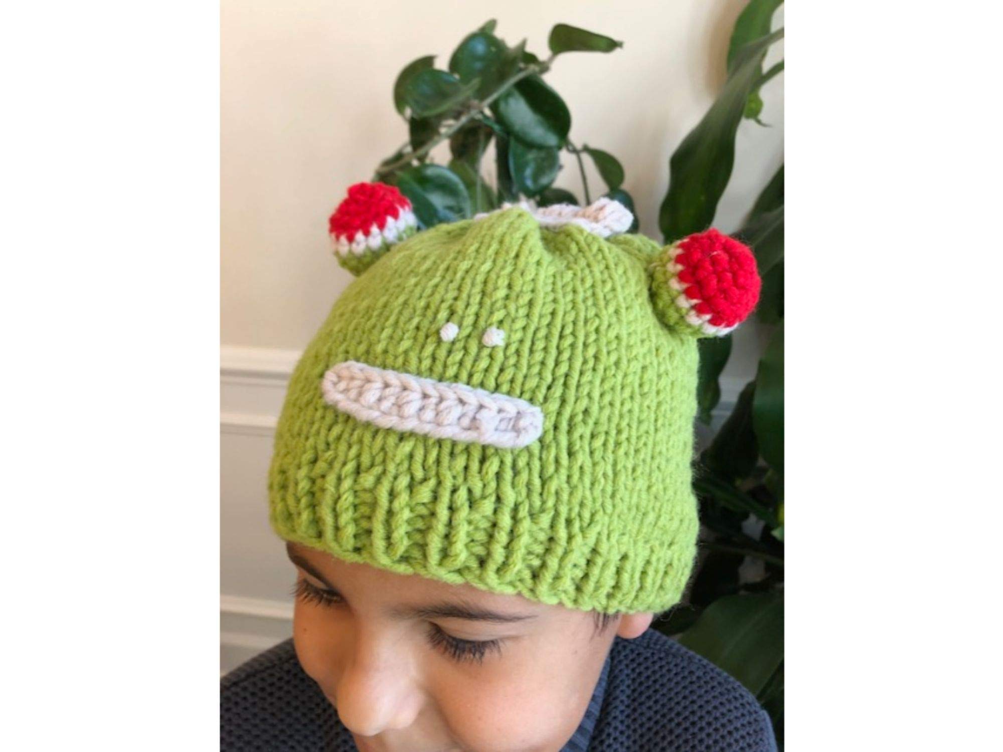 Hand-knitted frog wool beanie cap for kids, featuring a playful design and cozy fit, perfect for ages 2-7.