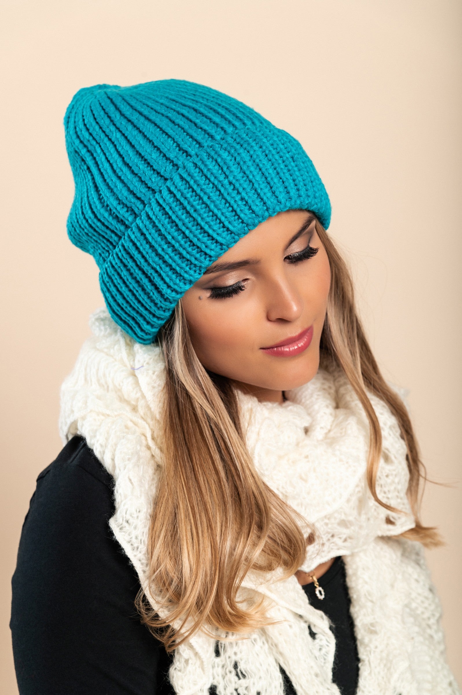 A stylish blue knitted hat made from soft fabric, featuring a ribbed knit design and rolled hem, perfect for winter wear.