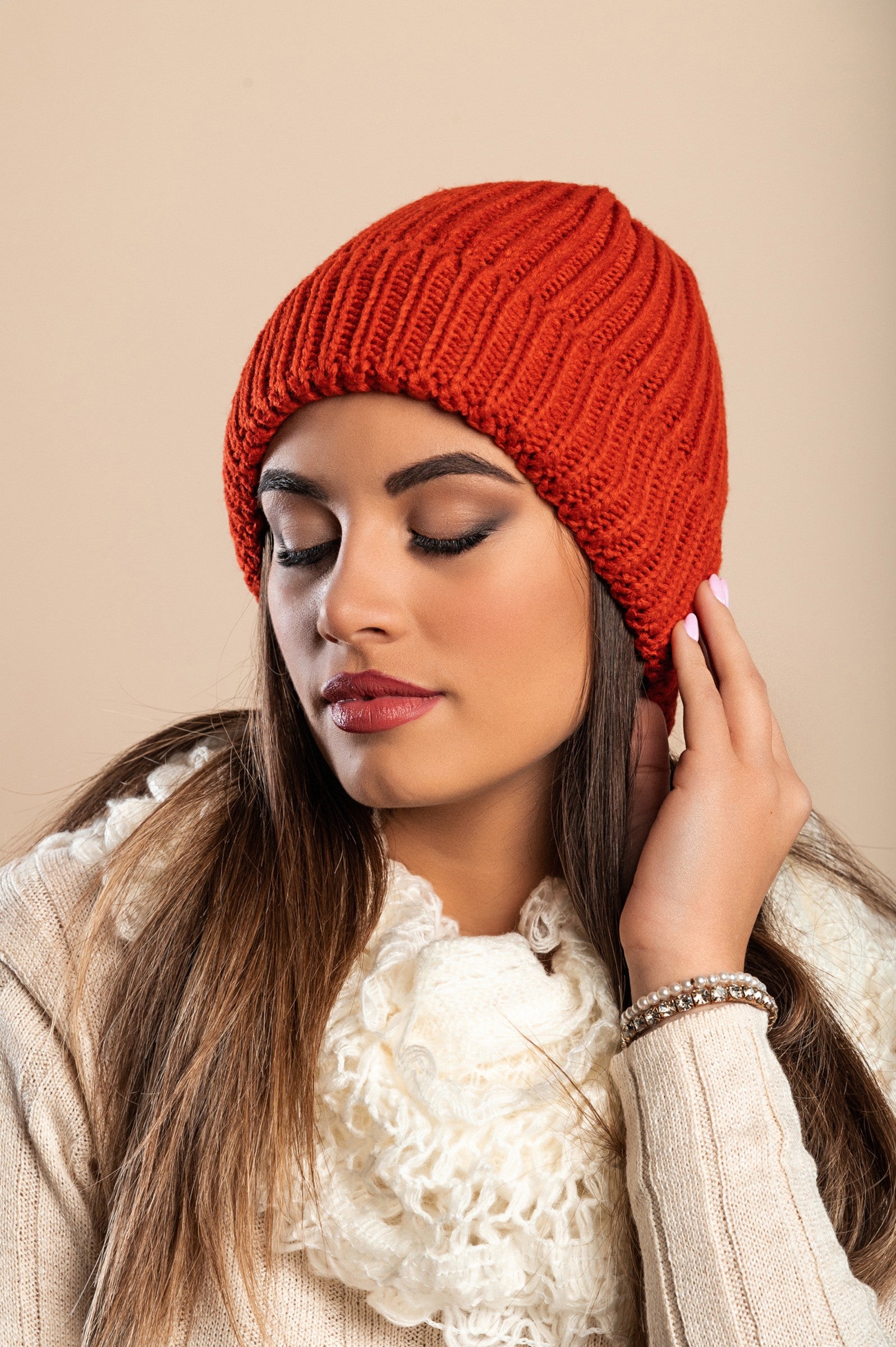 A stylish brick-colored knitted hat made from soft fabric, featuring a ribbed knit design and rolled hem for comfort.