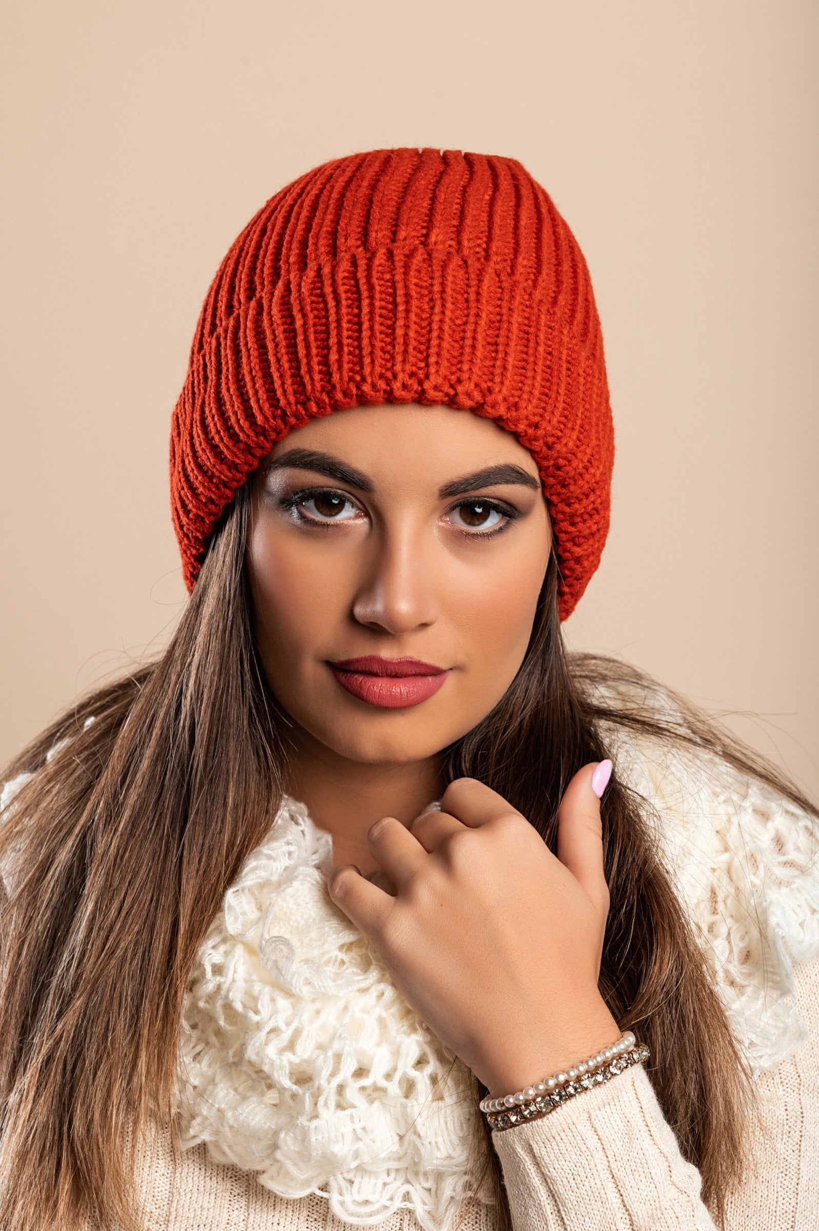 A stylish brick-colored knitted hat made from soft fabric, featuring a ribbed knit design and rolled hem.