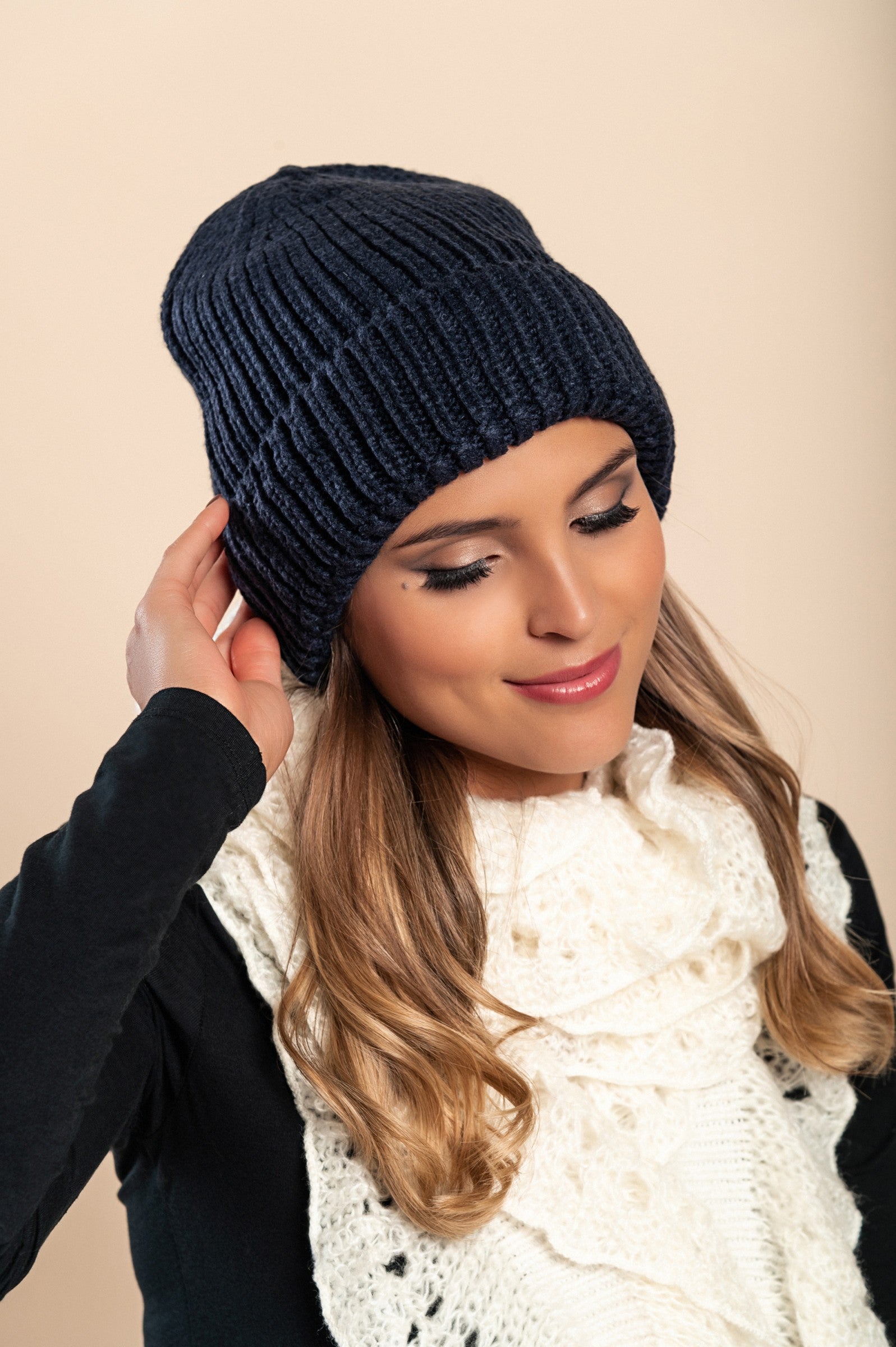 A stylish dark blue knitted hat featuring a ribbed knit design and rolled hem, made from soft and warm fabric.