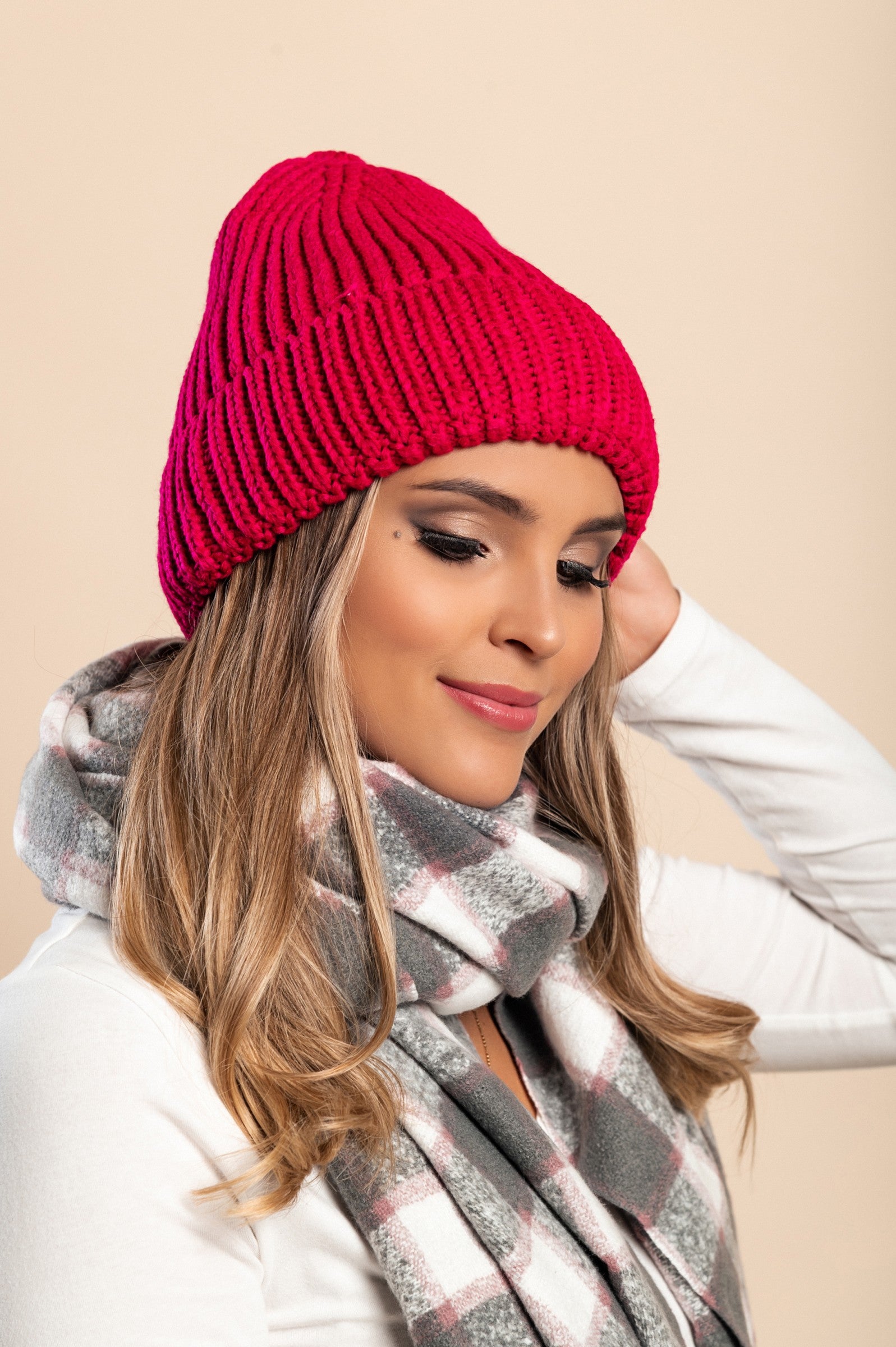 A stylish fuchsia knitted hat featuring a ribbed knit design and rolled hem, perfect for winter wear.