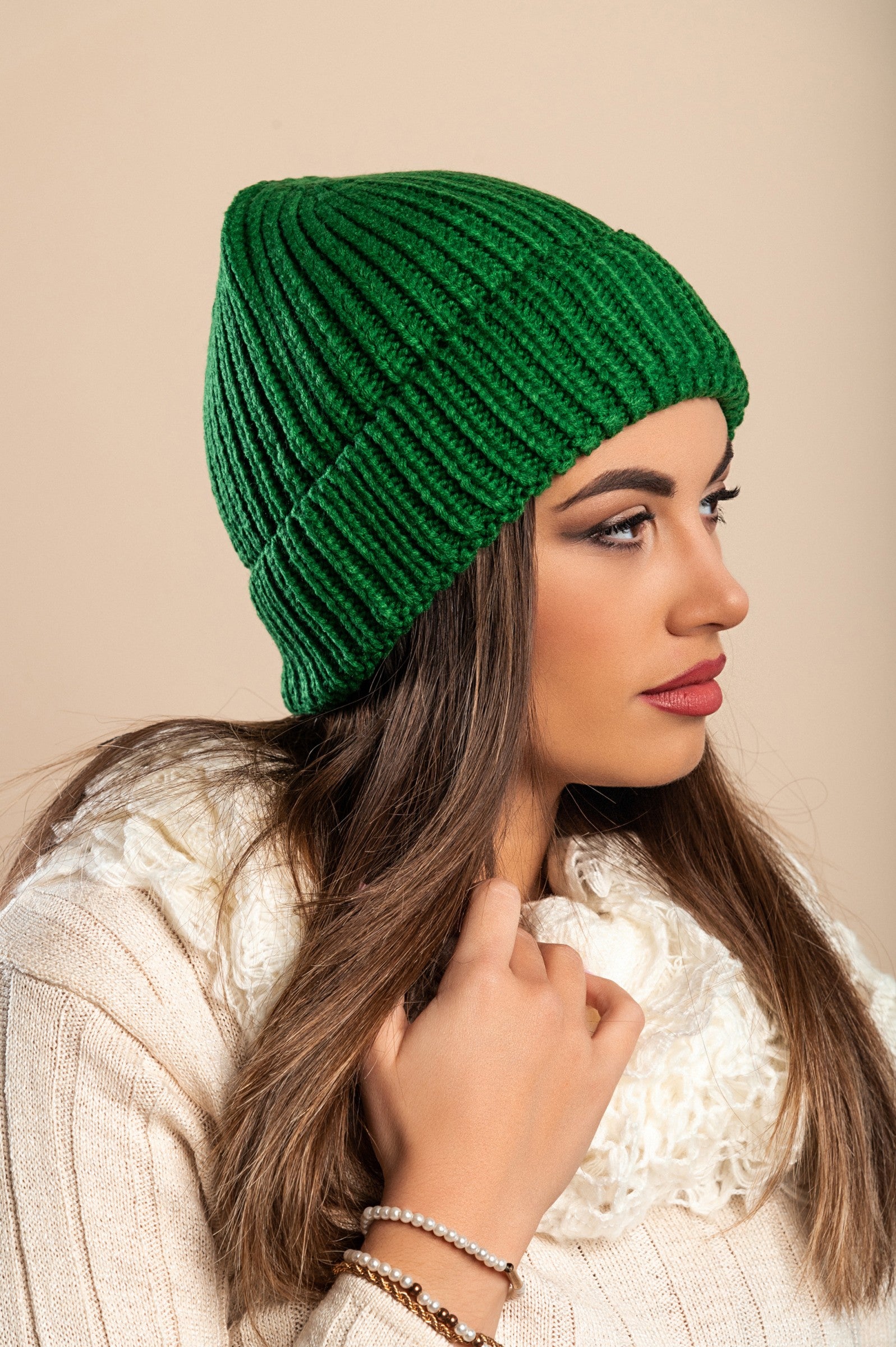 A cozy green knitted hat made from soft fabric, featuring a ribbed knit design and rolled hem, perfect for winter wear.