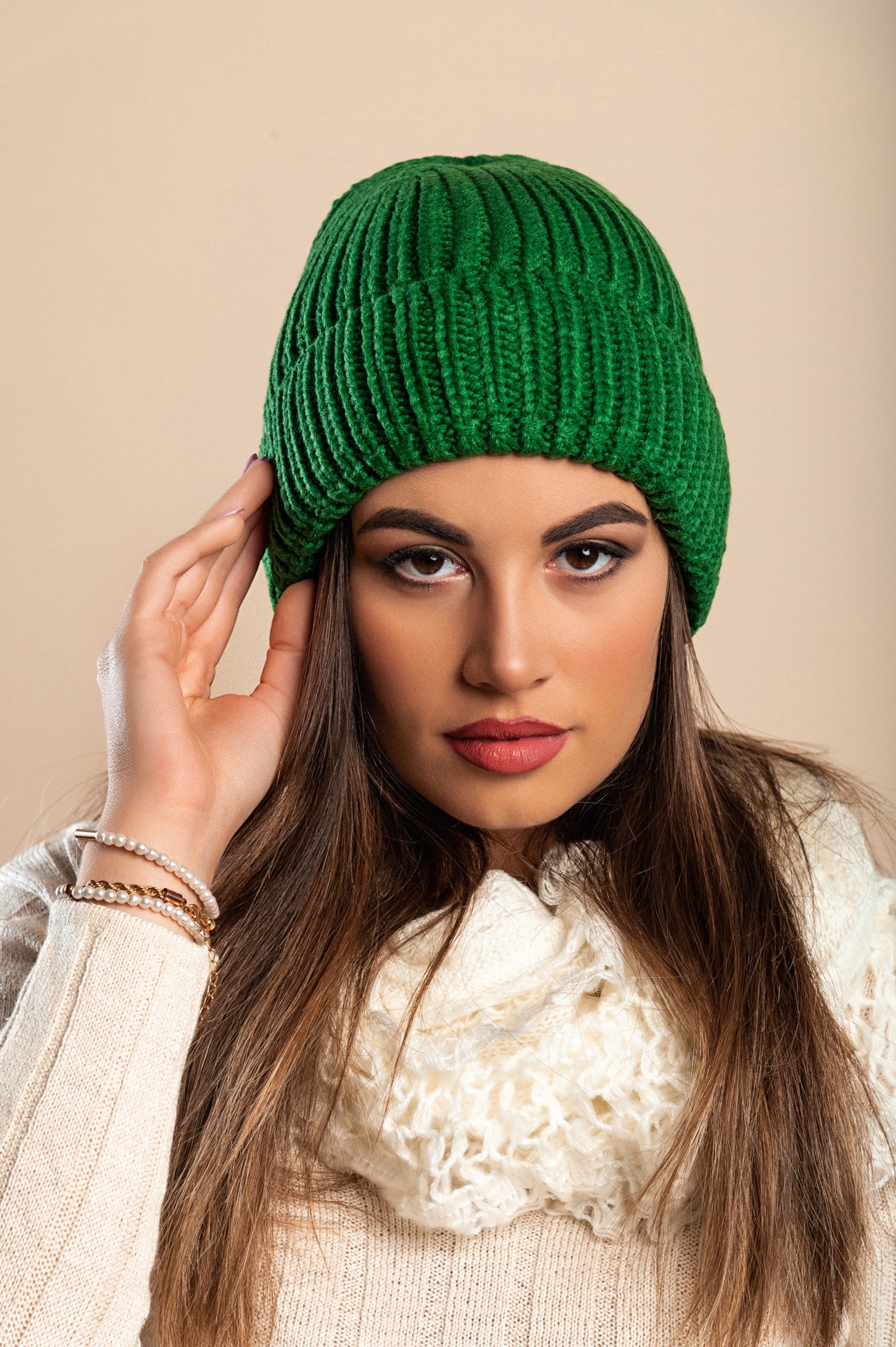 A stylish green knitted hat made from soft fabric, featuring a ribbed knit design and rolled hem for added comfort.