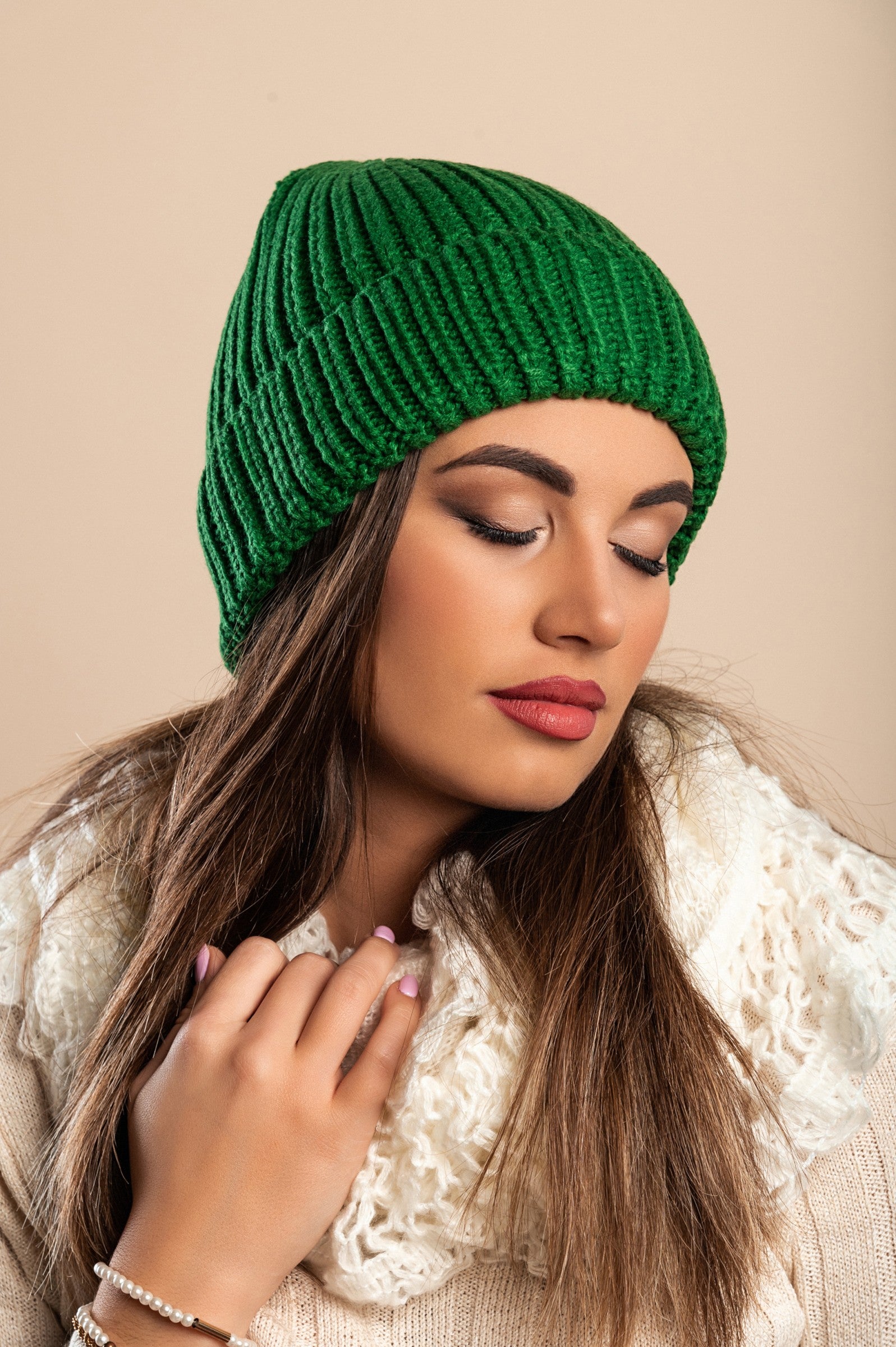 A stylish green knitted hat made from soft fabric, featuring a ribbed knit design and rolled hem for added comfort.