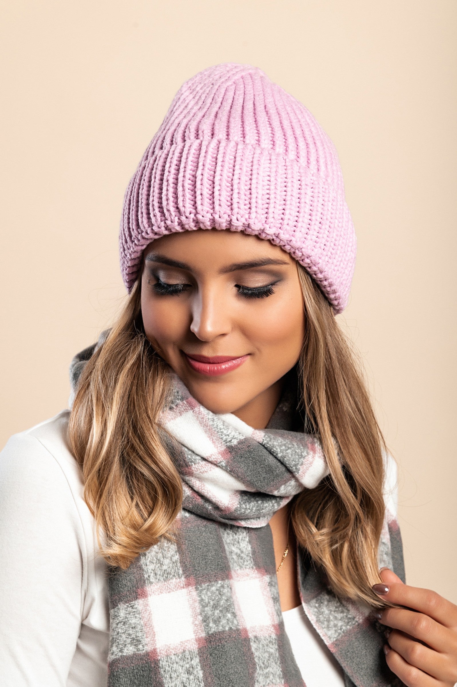 Light pink knitted hat made of soft fabric with a ribbed knit design and rolled hem.