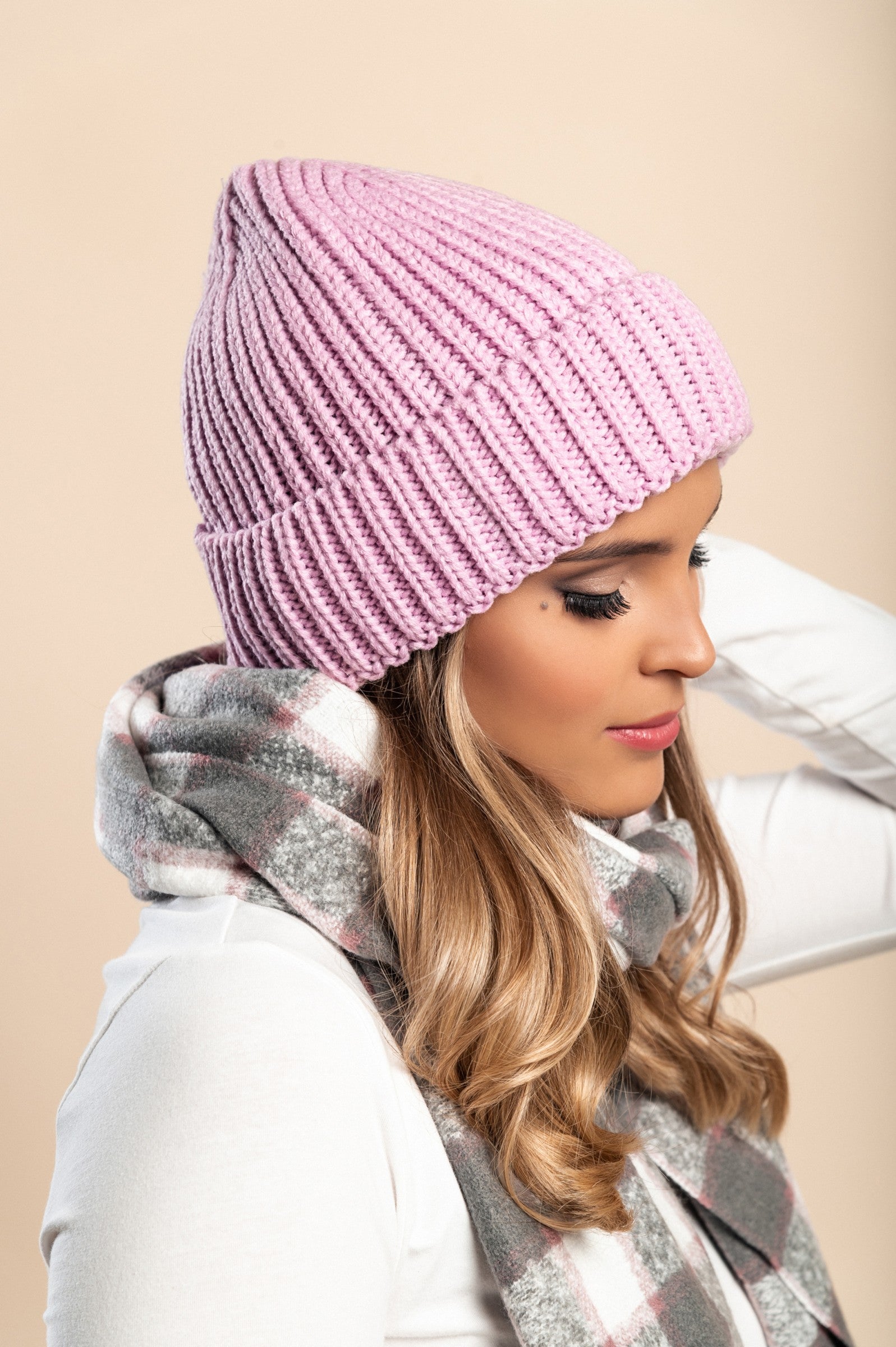 Light pink knitted hat made of soft fabric with a ribbed knit design and rolled hem, perfect for winter wear.