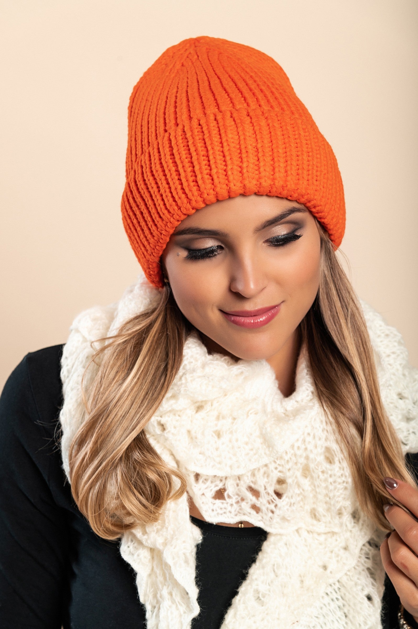 A vibrant orange knitted hat made from soft fabric, featuring a ribbed knit design and rolled hem for added style and comfort.