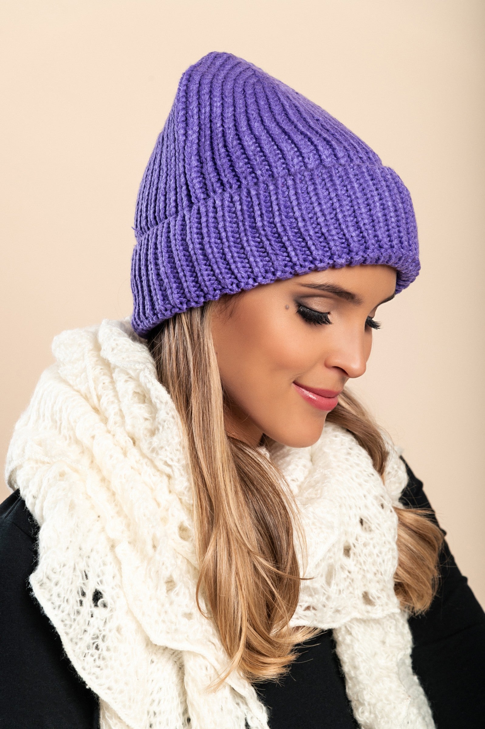 A stylish purple knitted hat made from soft fabric, featuring a ribbed knit design and rolled hem, perfect for winter wear.