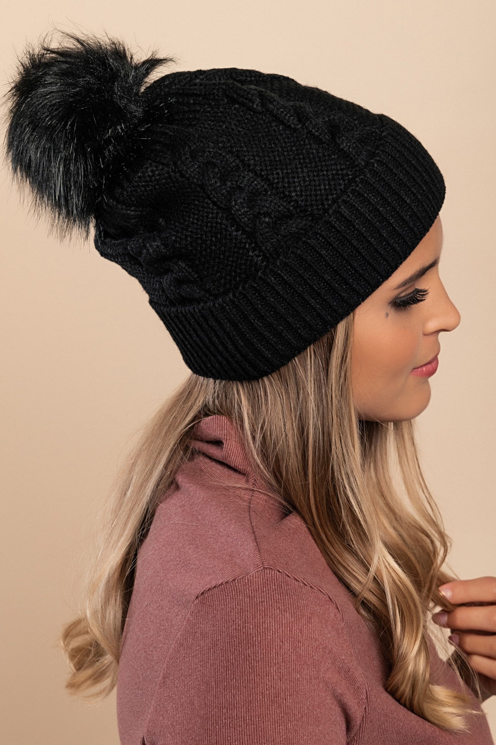 Black knitted hat with a faux fur pompom, featuring a rolled edge design, made from soft acrylic fabric.