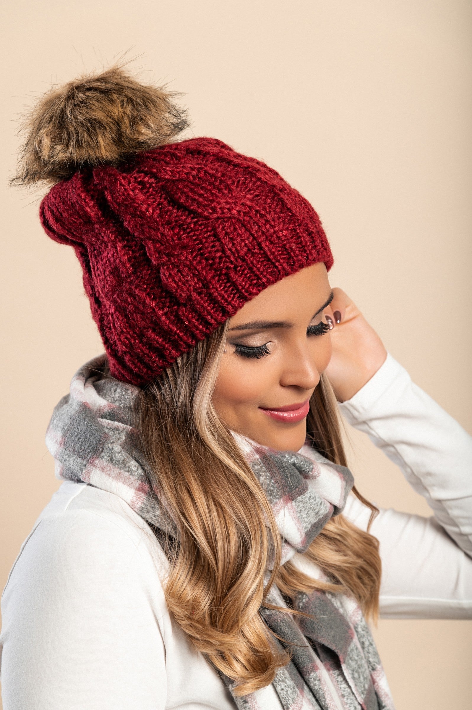 Red knitted hat with sequins and faux fur pompom, showcasing a stylish rolled edge design.