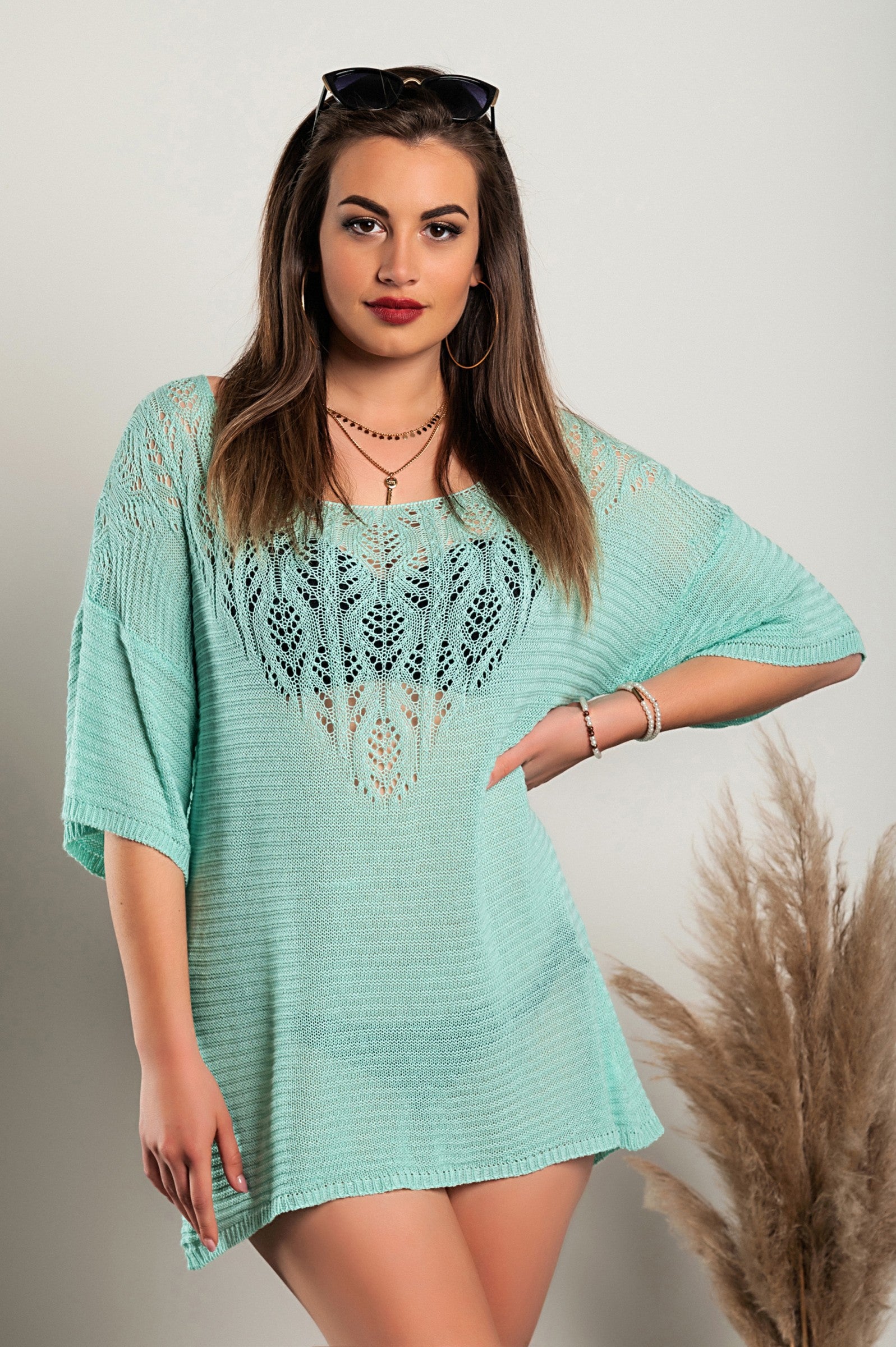 Turquoise knitted mini dress featuring hole detail, showcasing a loose fit, short sleeves, and wide neckline.