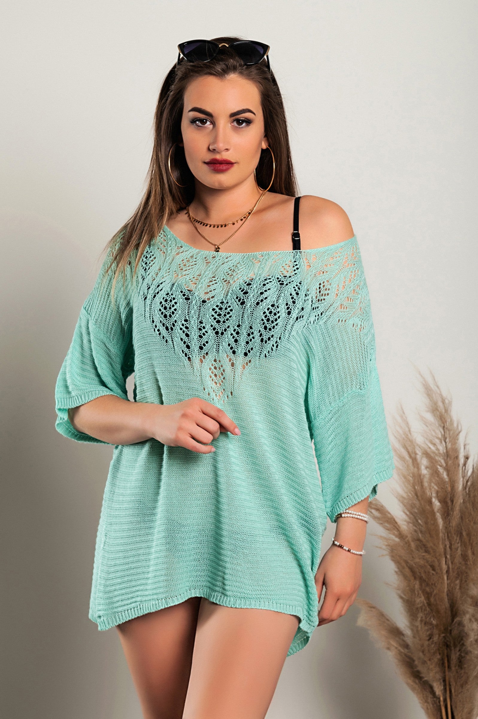 Turquoise knitted mini dress featuring hole detail, showcasing a loose fit, short sleeves, and wide neckline.