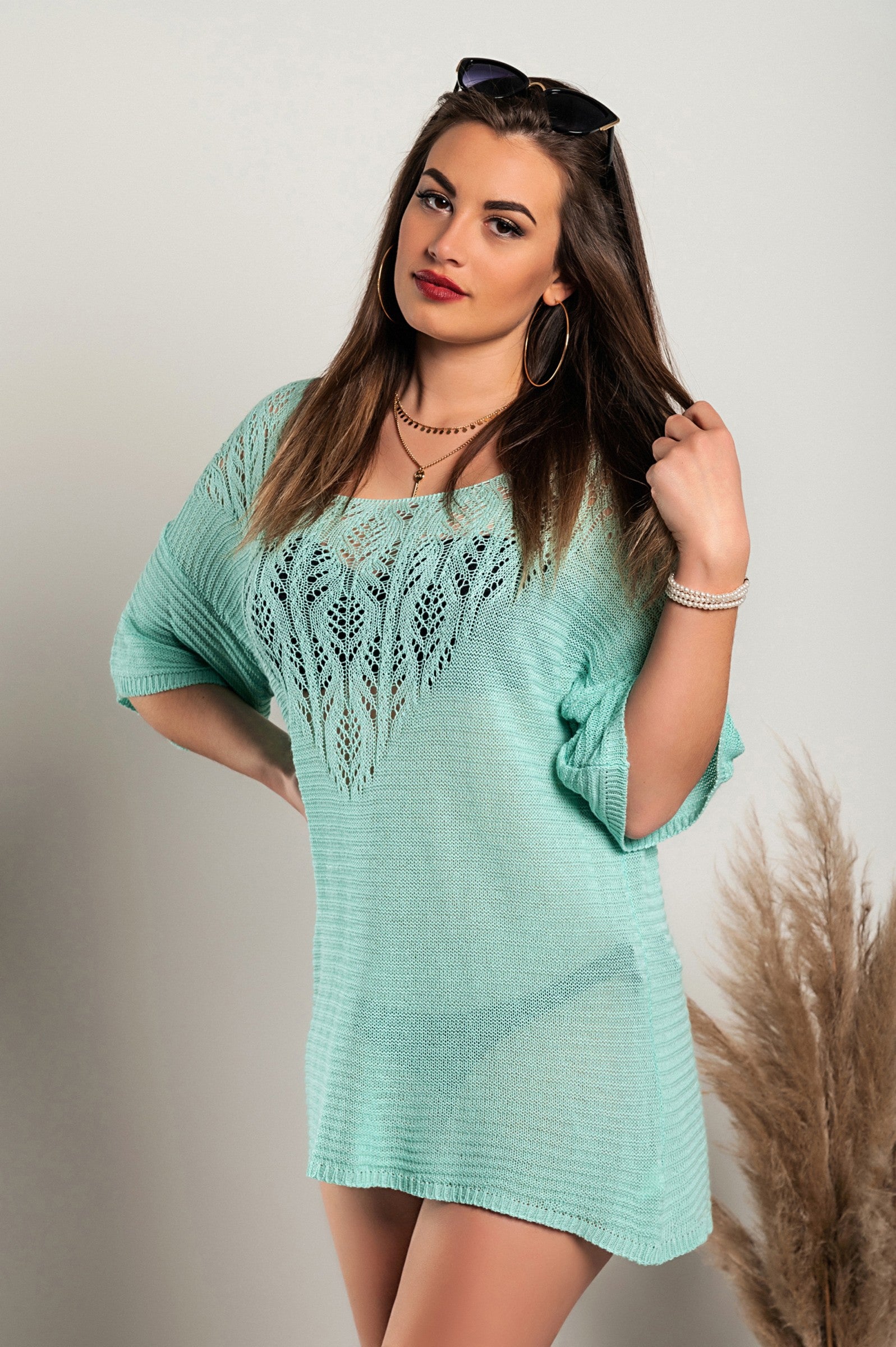 Turquoise knitted mini dress featuring hole detail, showcasing a loose fit, short sleeves, and wide neckline.