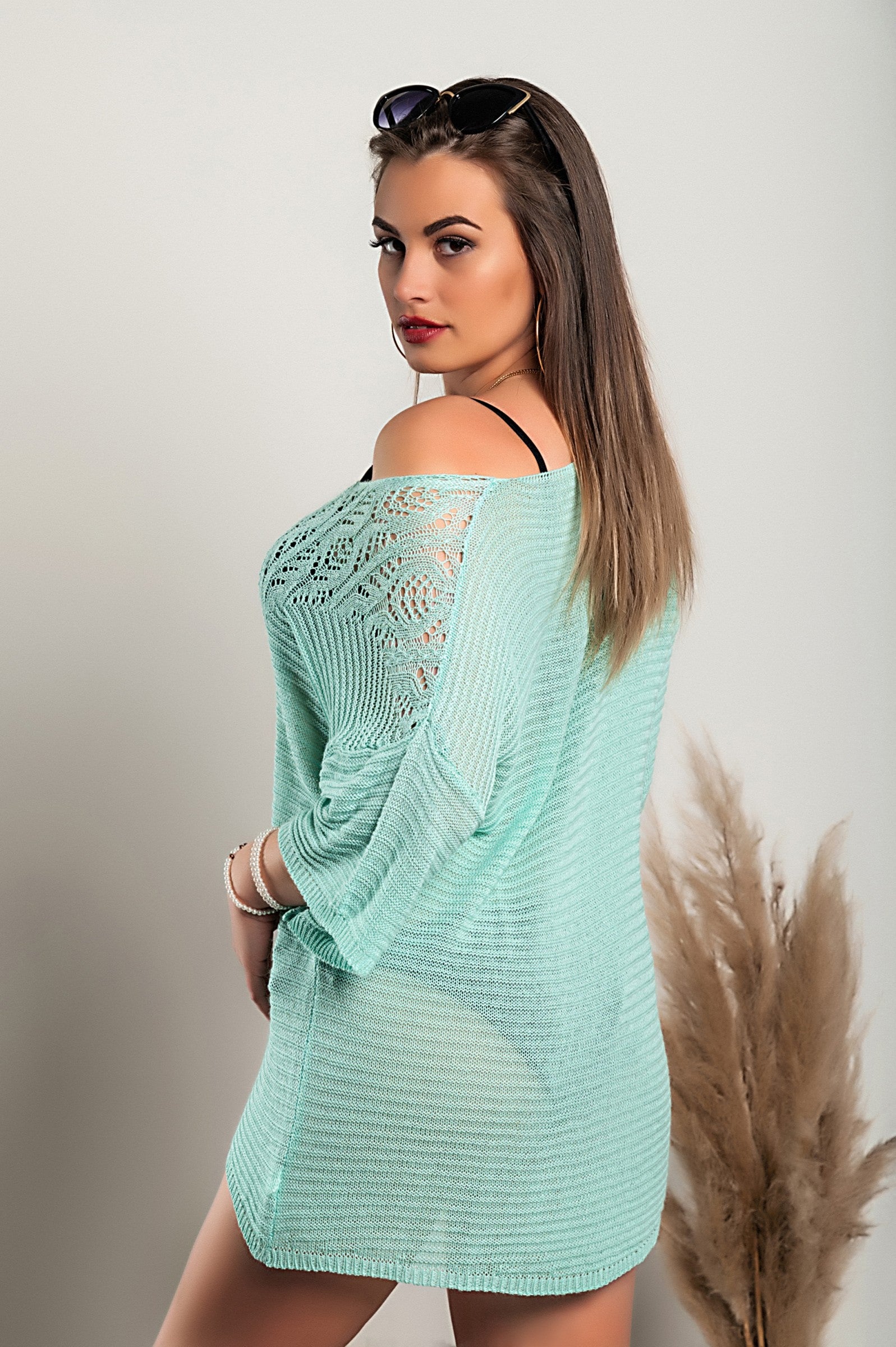 Turquoise knitted mini dress featuring hole detail, showcasing a loose fit, short sleeves, and wide neckline.