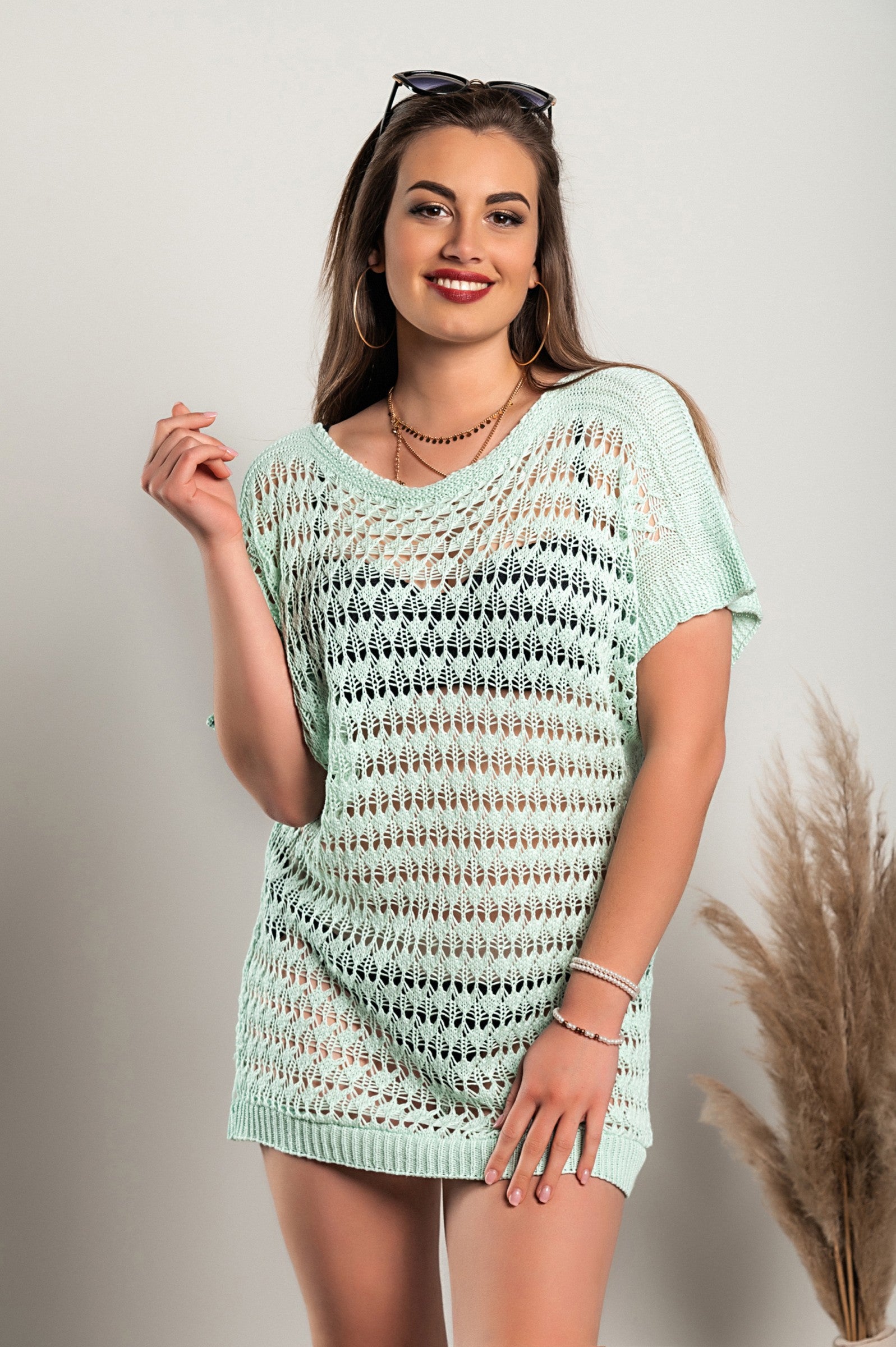 Light green knitted mini dress with short sleeves, featuring a wide neckline and unique hole details, made in Italy.